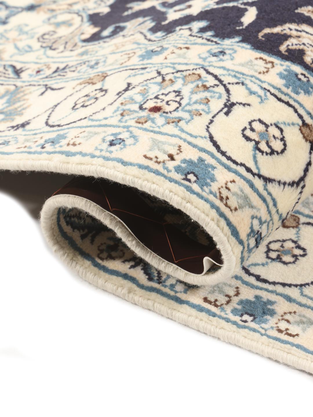 A hand-knotted Nain rug from the Middle East with a navy blue and cream floral medallion design.