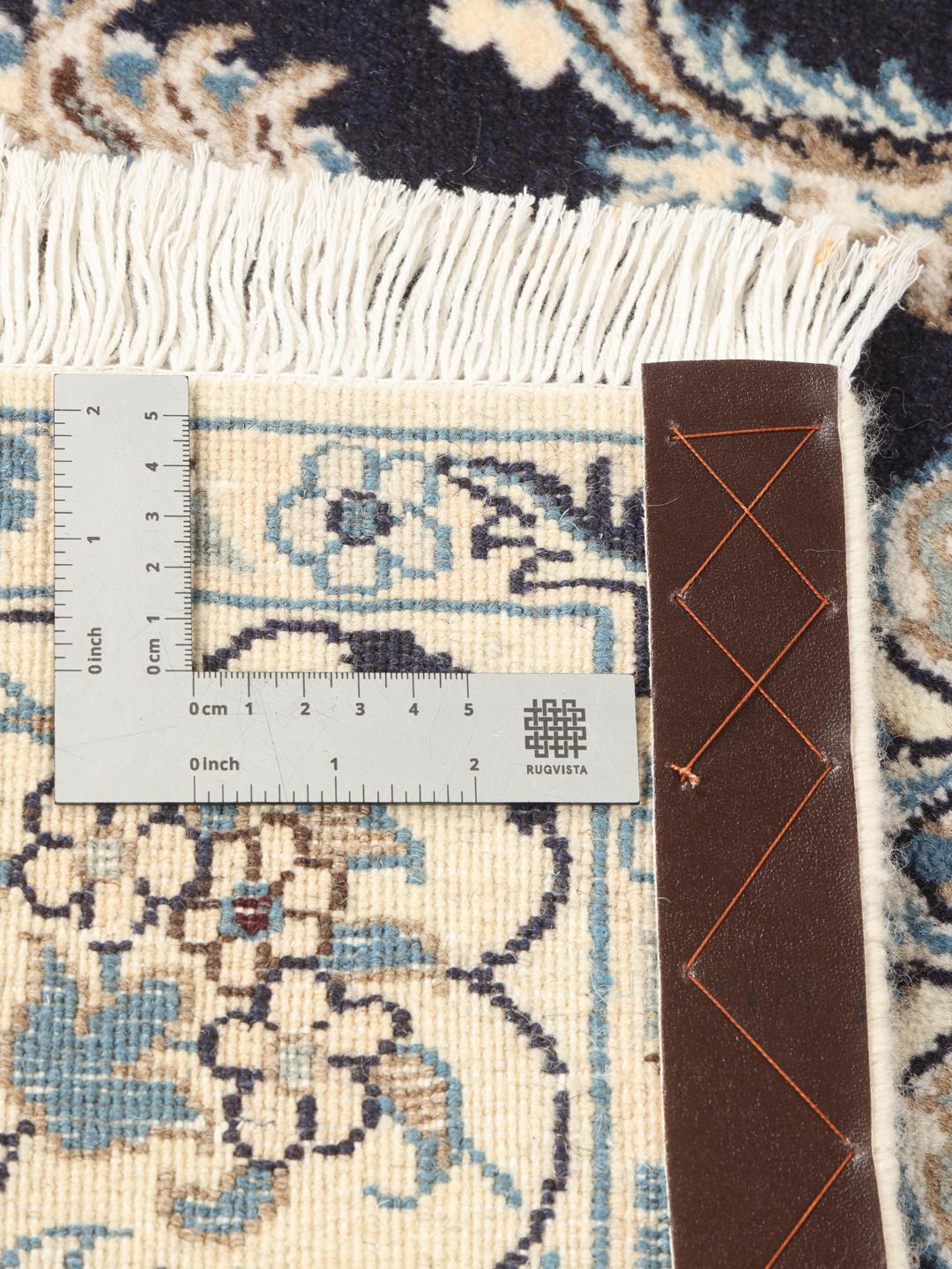 A hand-knotted Nain rug from the Middle East with a navy blue and cream floral medallion design.