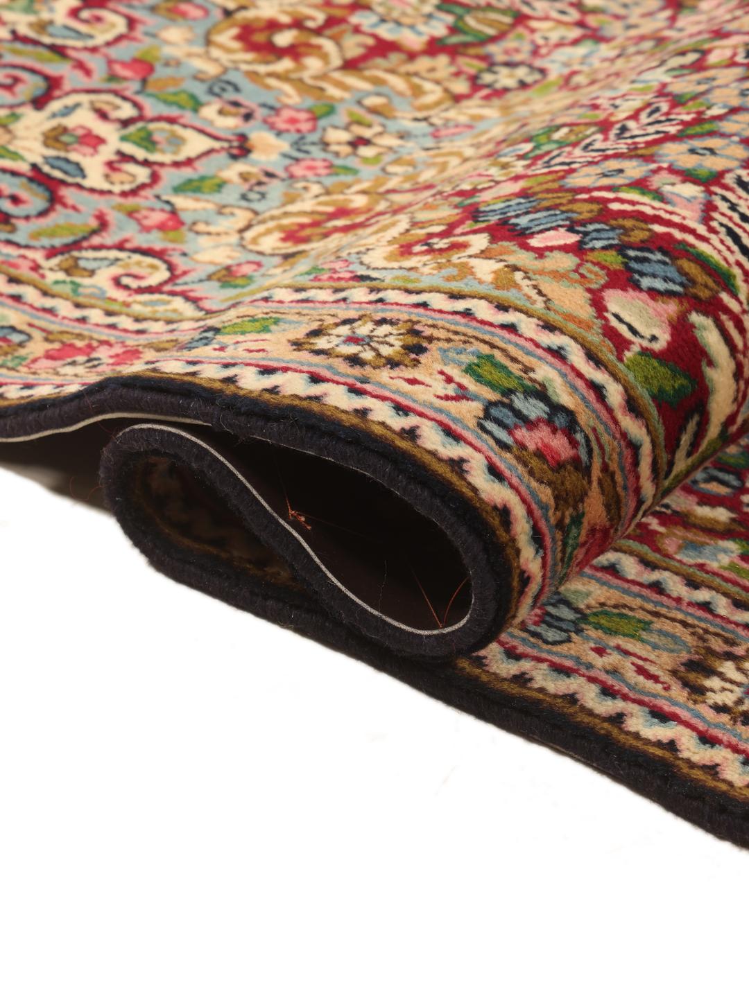 A large, rectangular Kerman rug from the Middle East featuring a complex red and dark red floral medallion pattern.