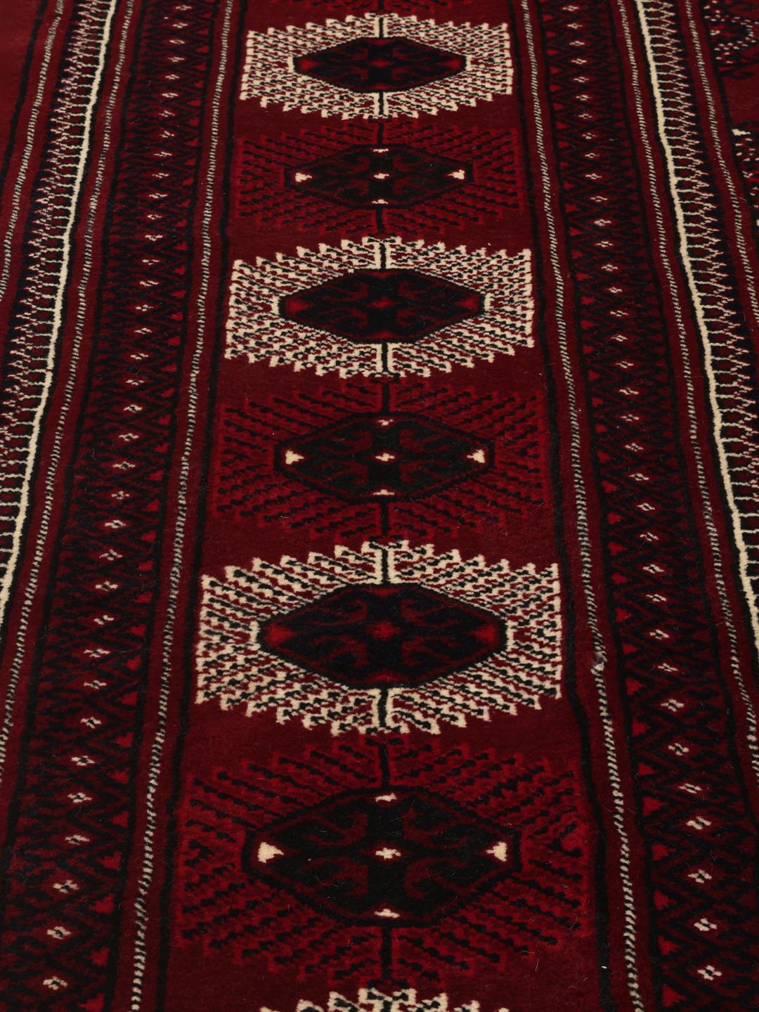 A hand-knotted Turkaman rug from the Middle East in deep red featuring traditional geometric motifs.
