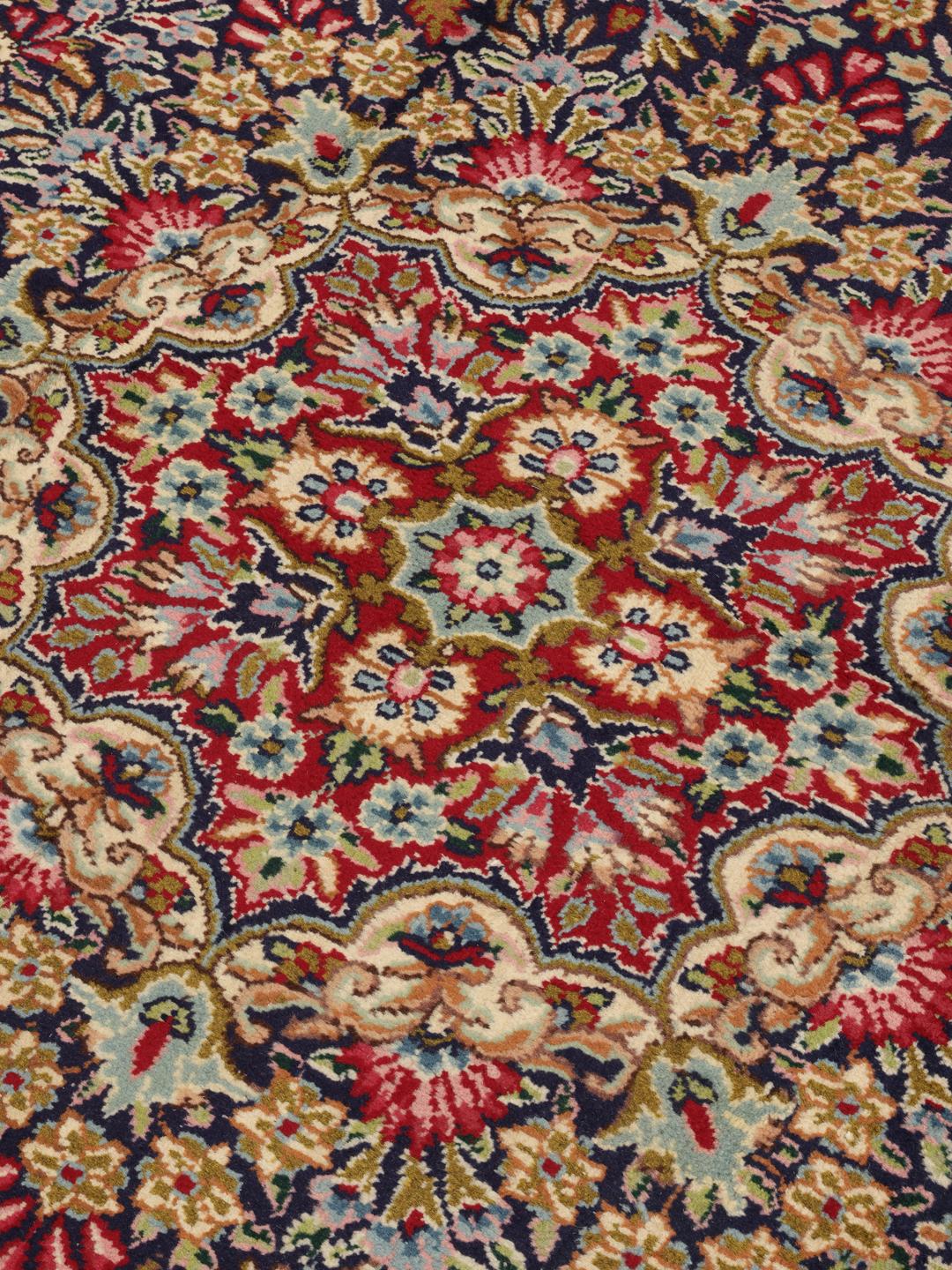 Een handgeknoopt Kerman Sherkat Farsh-tapijt met ingewikkelde florale patronen in rode en donkerblauwe tinten