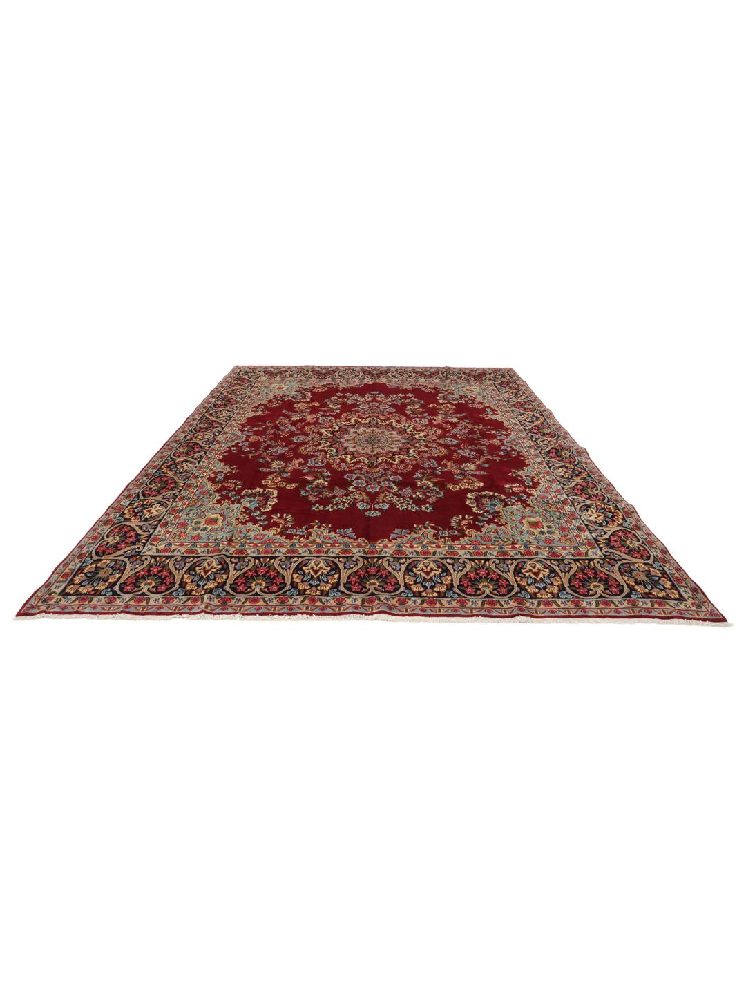 A hand-knotted Kerman rug with a large central floral medallion on a red field.