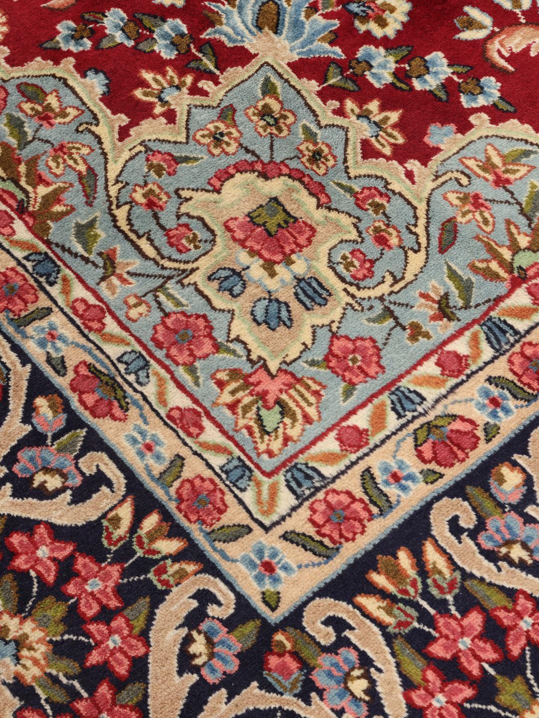 A hand-knotted Kerman rug with a large central floral medallion on a red field.