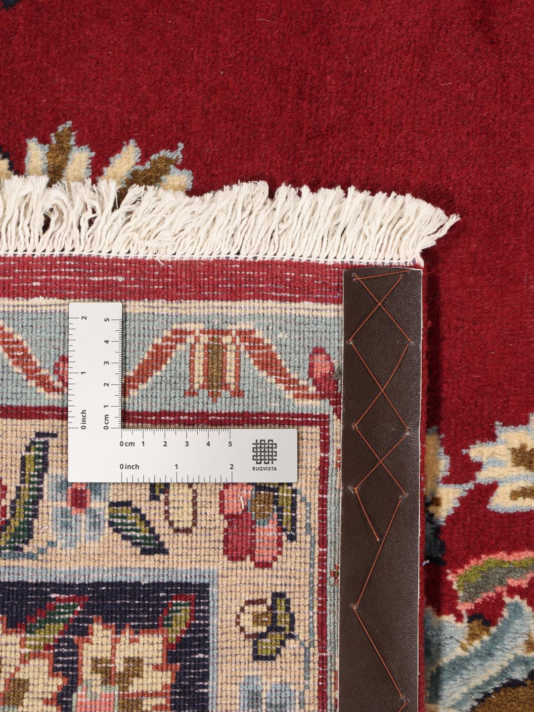 A hand-knotted Kerman rug with a large central floral medallion on a red field.