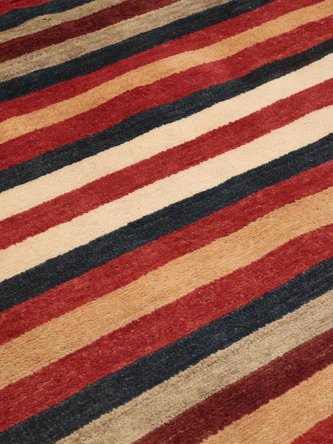 Een handgeknoopt Afghaans tapijt met horizontale strepen in rood, blauw en beige.