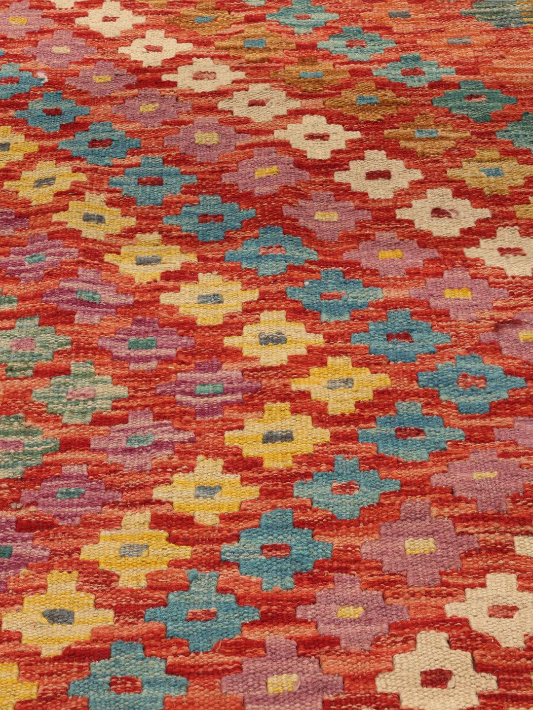 Een groot handgeweven Afghan Kelim-tapijt met een levendig veelkleurig geometrisch patroon