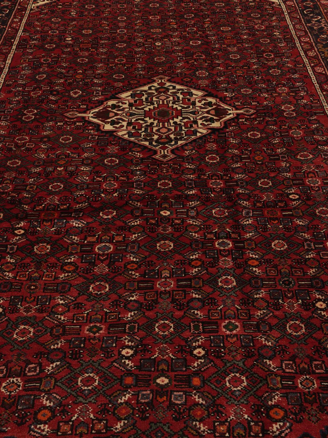 Hand-knotted Hosseinabad rug from the Middle East in deep red and dark blue tones.