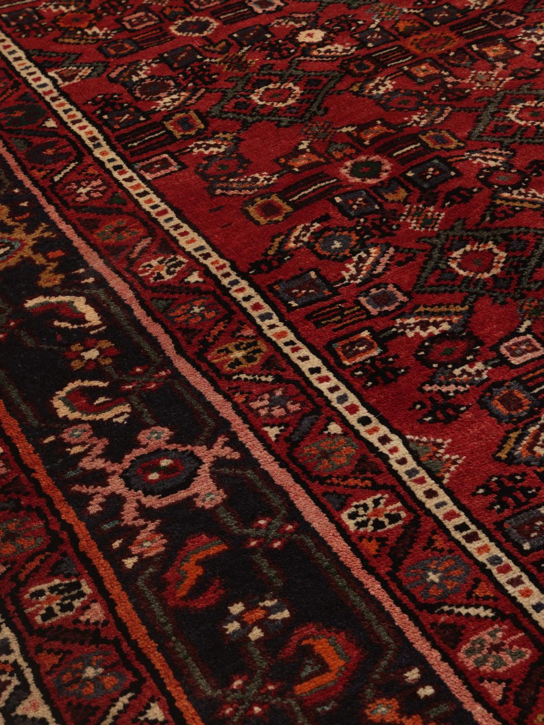 Hand-knotted Hosseinabad rug from the Middle East in deep red and dark blue tones.