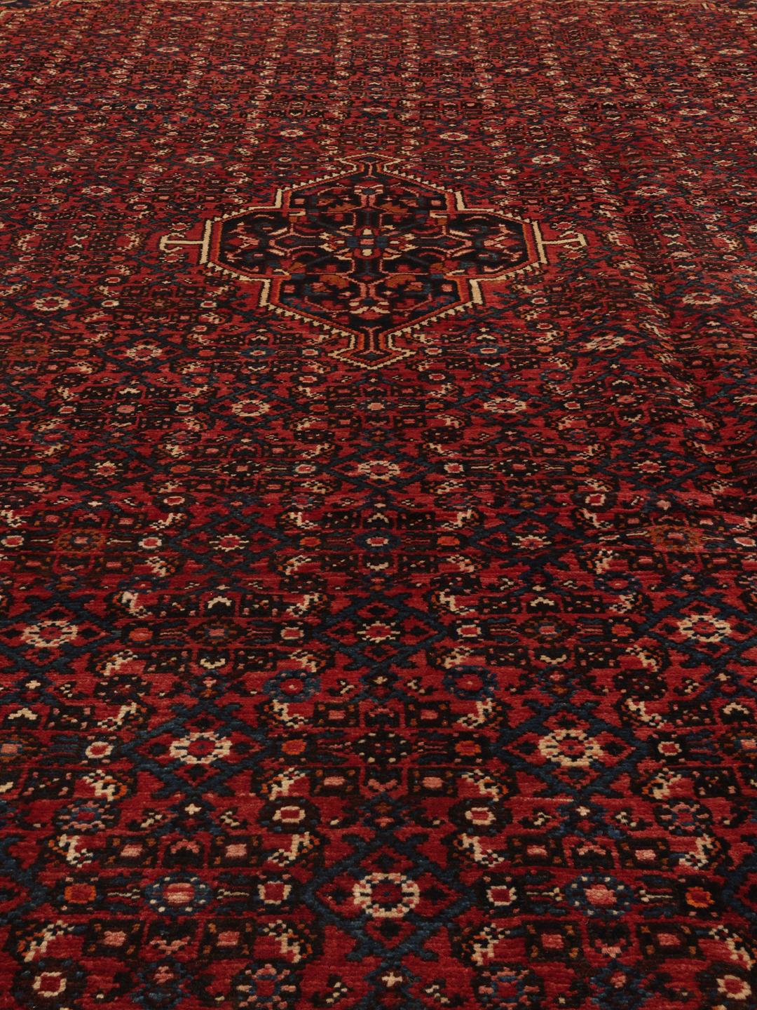 A hand-knotted Hosseinabad rug featuring a traditional dark-red field and detailed patterns.