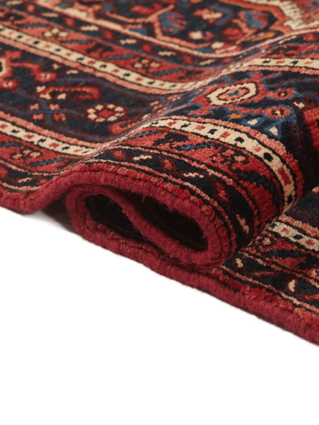 A hand-knotted Hosseinabad rug featuring a traditional dark-red field and detailed patterns.