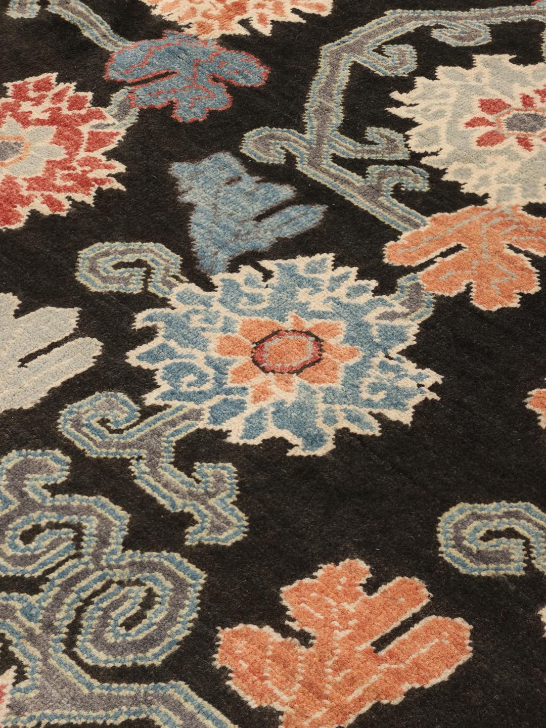 Hand-knotted Afghan Kazak rug with floral patterns on a black field