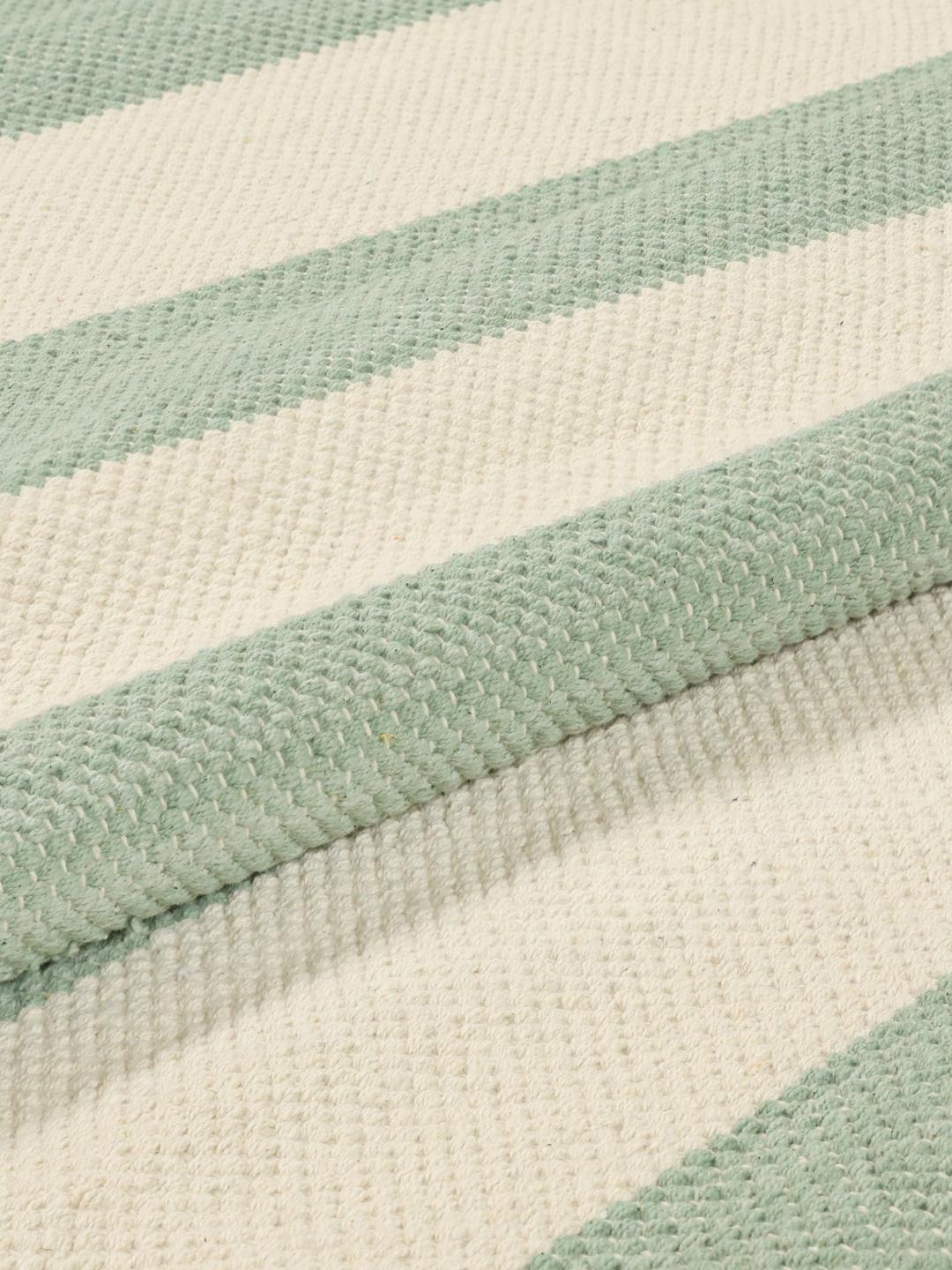 A hand-woven cotton rug featuring a mint green and cream striped pattern with fringe ends.
