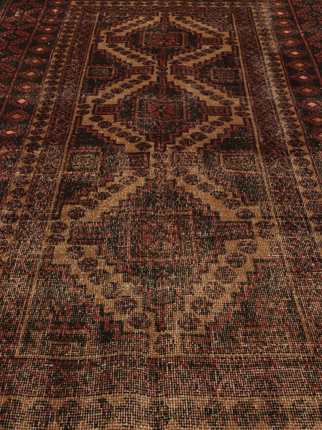 Håndknyttet Beluch-tæppe med en mørkerød patina og traditionelle geometriske motiver.