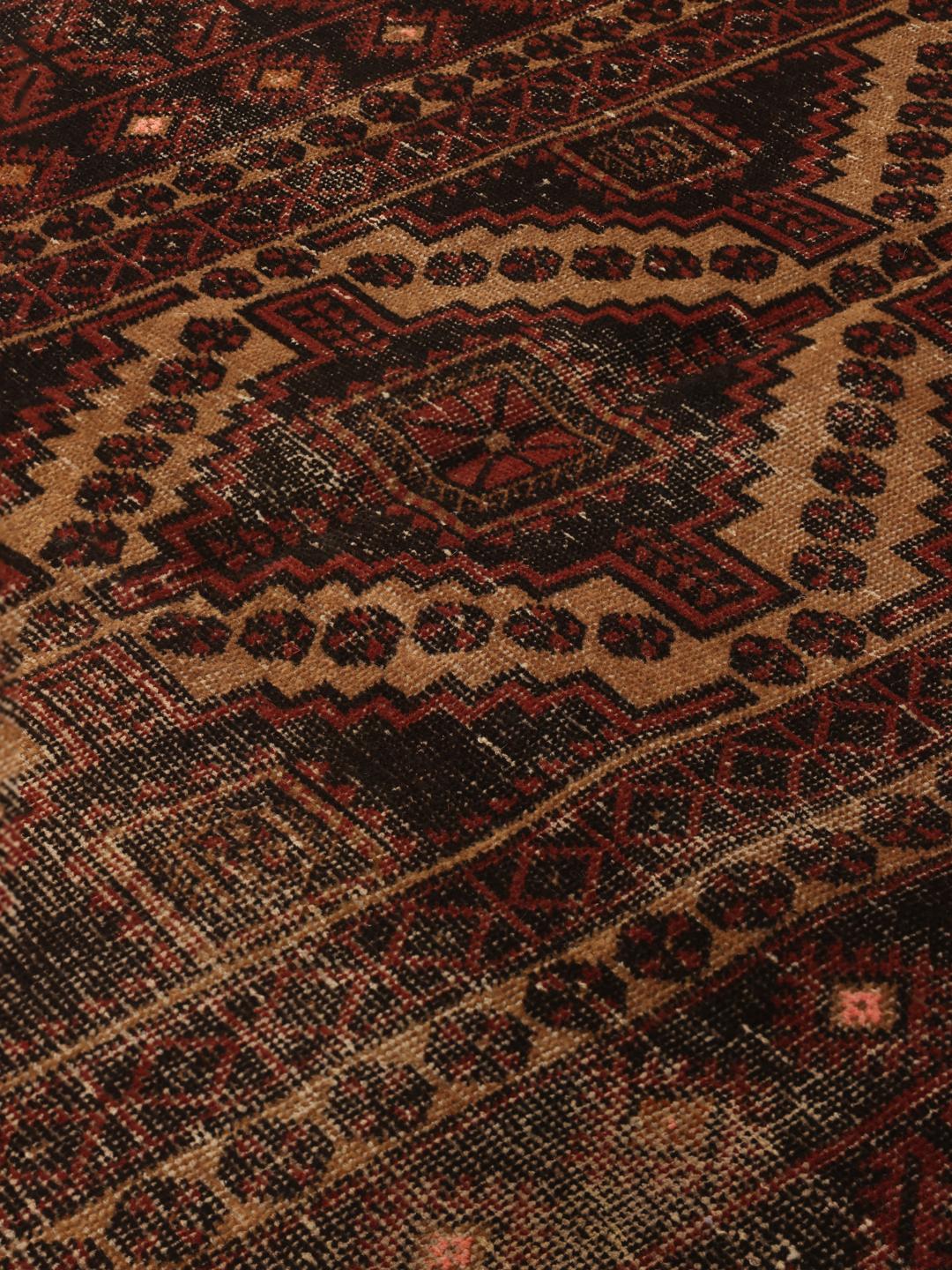 Håndknyttet Beluch-tæppe med en mørkerød patina og traditionelle geometriske motiver.