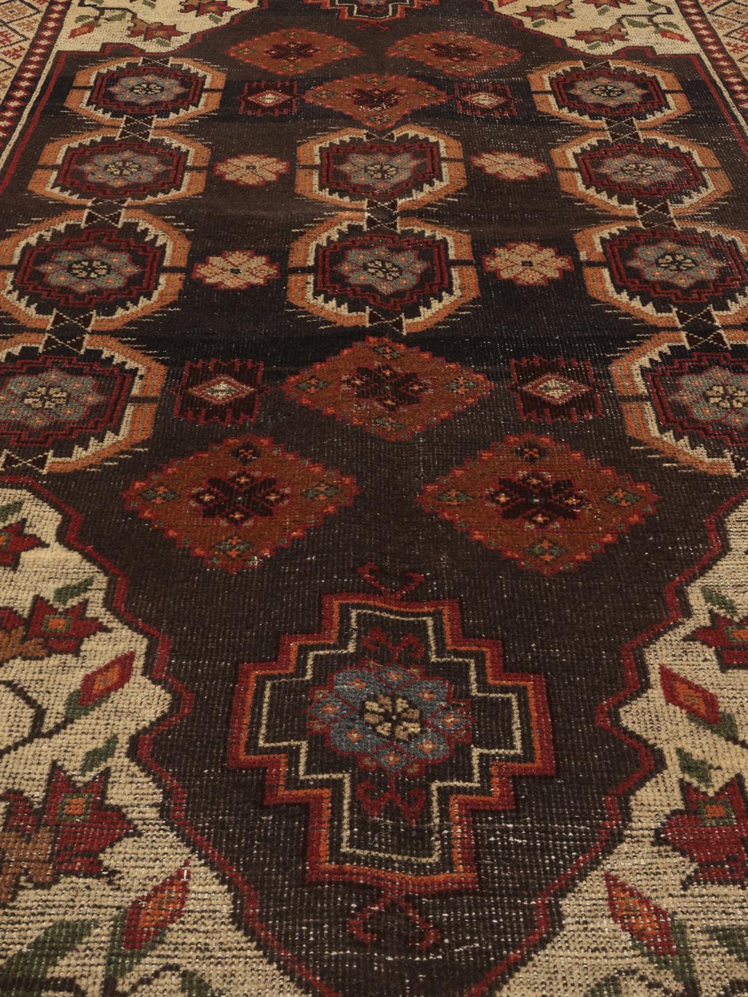Een handgeknoopt tapijt uit het Midden-Oosten met een donker centraal medaillon en bloemrijke hoeken in tinten rood, beige en blauw.