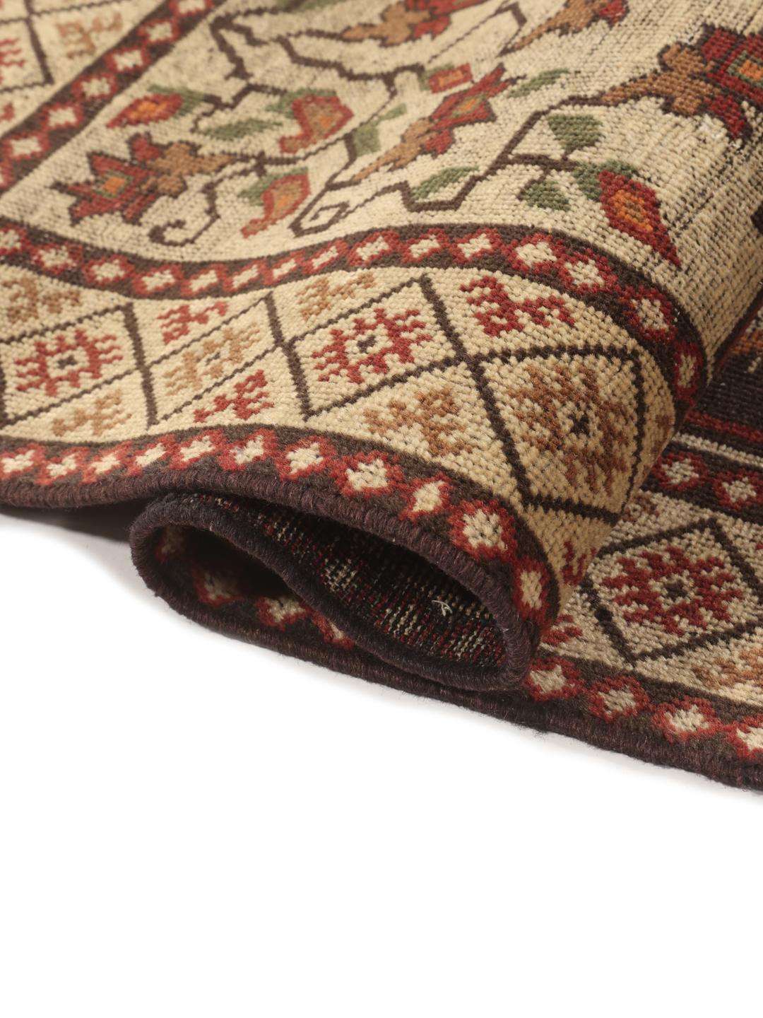 Een handgeknoopt tapijt uit het Midden-Oosten met een donker centraal medaillon en bloemrijke hoeken in tinten rood, beige en blauw.