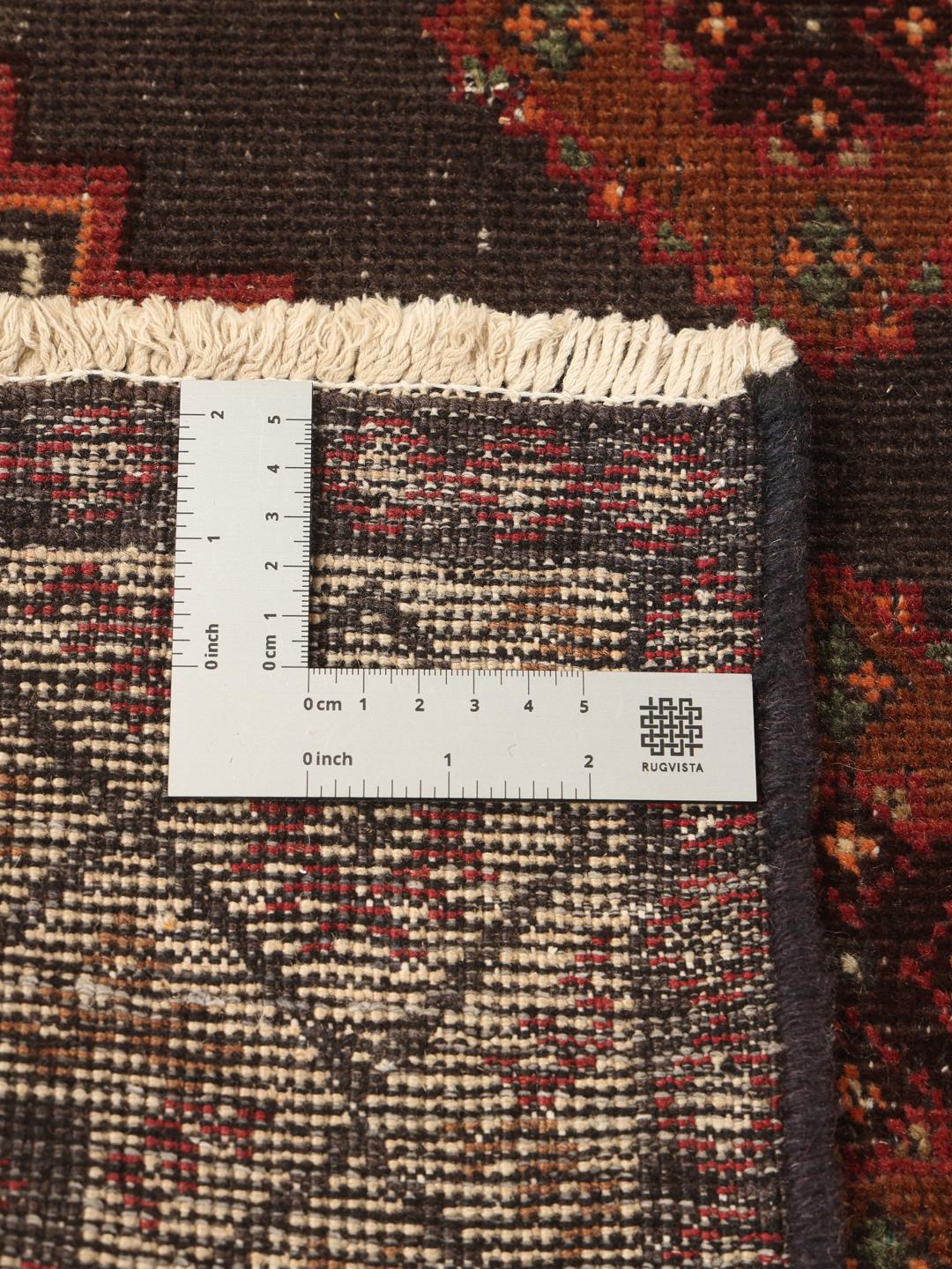 Een handgeknoopt tapijt uit het Midden-Oosten met een donker centraal medaillon en bloemrijke hoeken in tinten rood, beige en blauw.