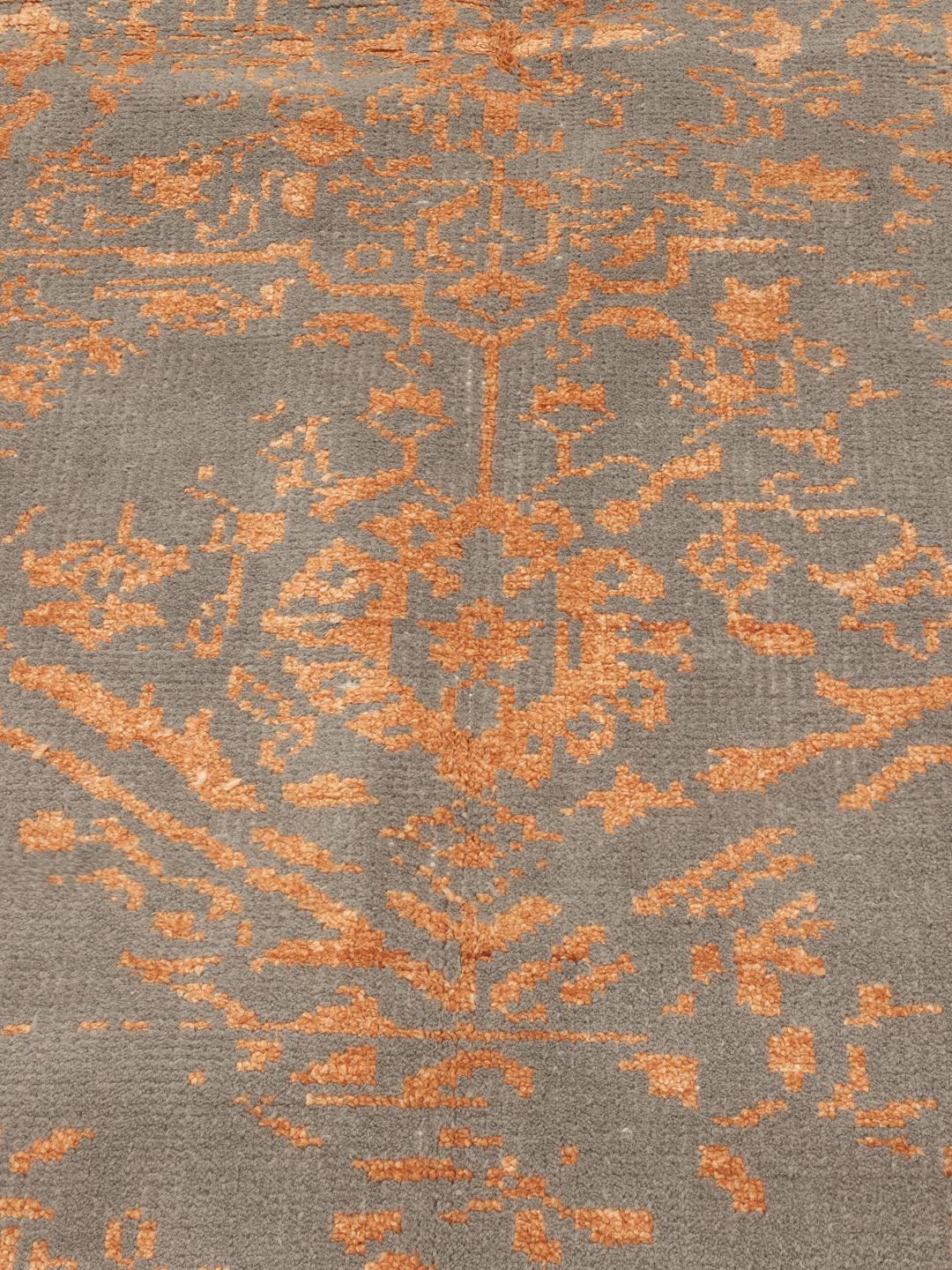 Een rechthoekig tapijt met een oranje bloemenpatroon op een grijze achtergrond