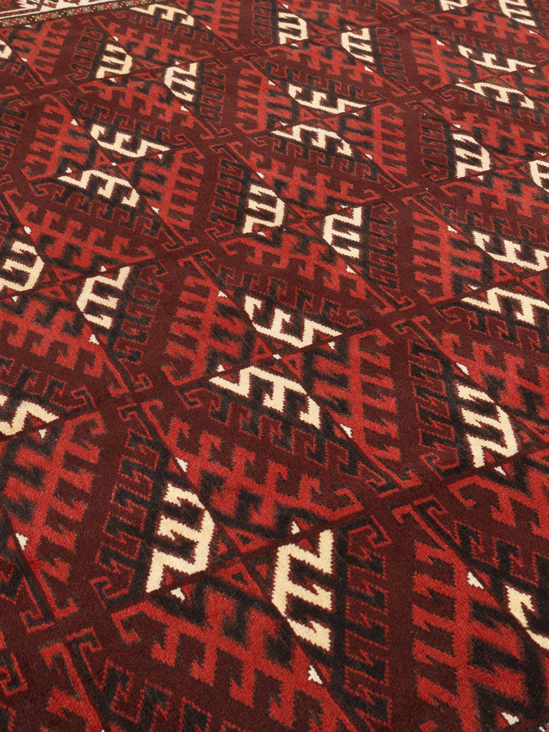 A hand-knotted Turkaman rug from the Middle East featuring a dark-red field and geometric patterns.