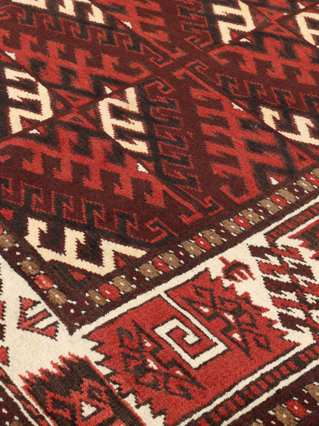 A hand-knotted Turkaman rug from the Middle East featuring a dark-red field and geometric patterns.