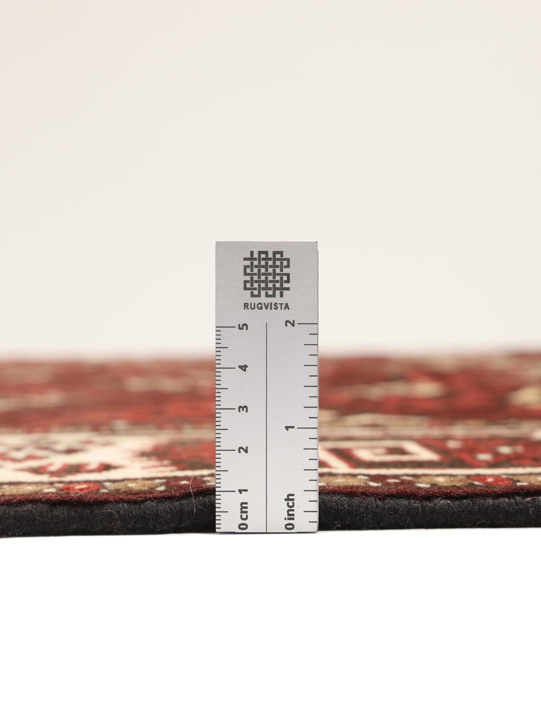 A hand-knotted Turkaman rug from the Middle East featuring a dark-red field and geometric patterns.