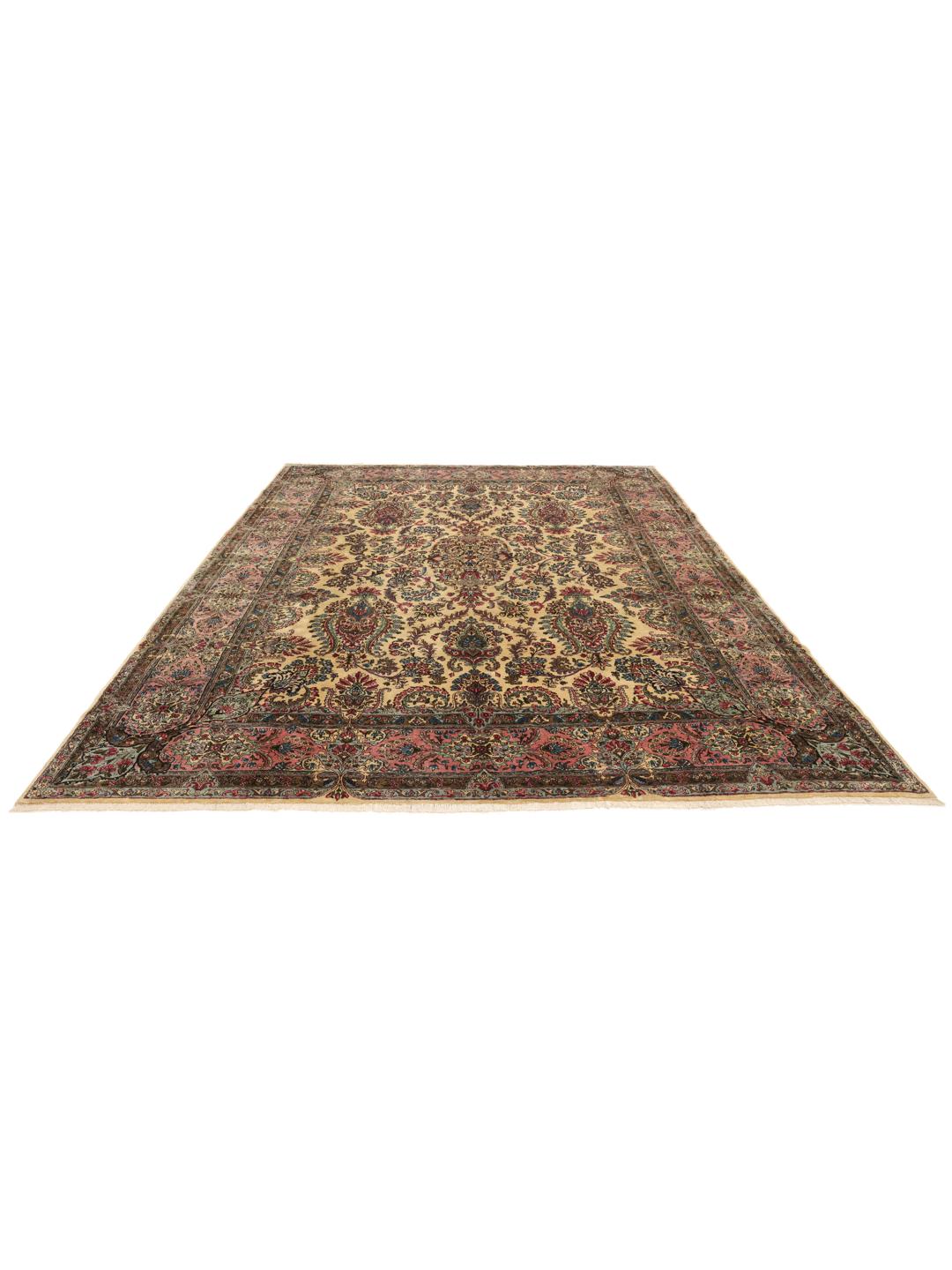 A large hand-knotted Middle Eastern Kerman rug with intricate floral patterns in beige and pink.