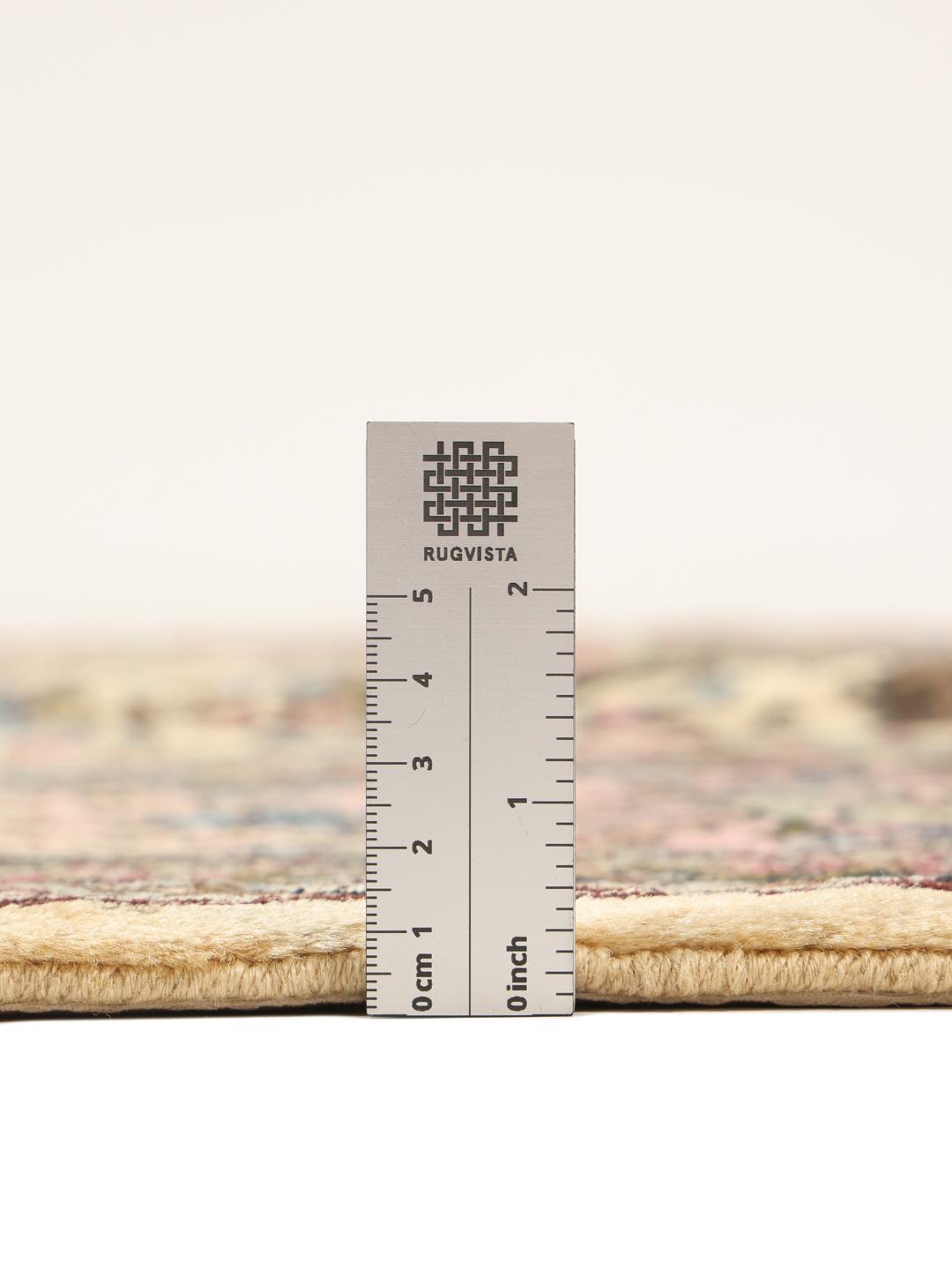A large hand-knotted Middle Eastern Kerman rug with intricate floral patterns in beige and pink.