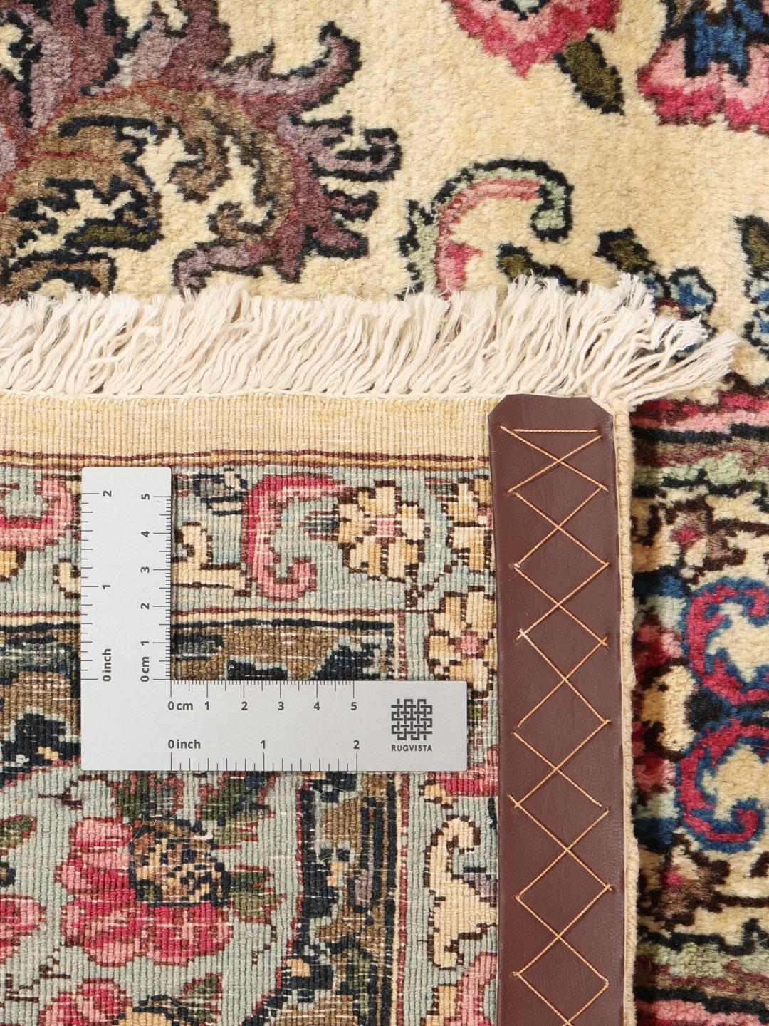 A large hand-knotted Middle Eastern Kerman rug with intricate floral patterns in beige and pink.