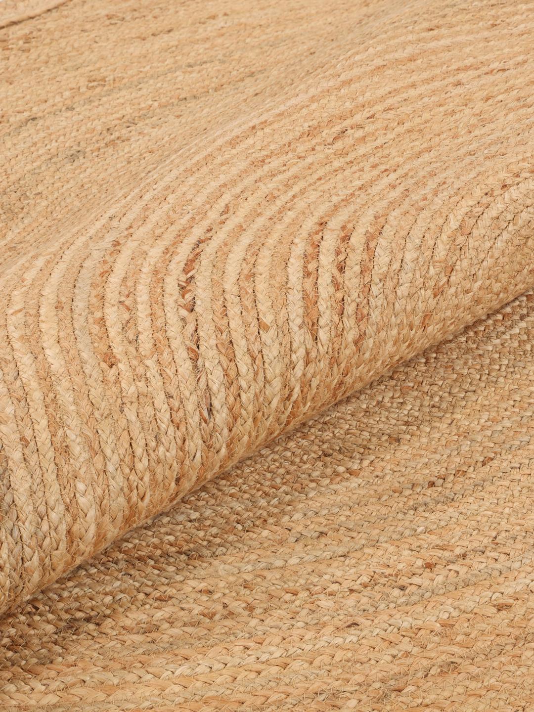 Rundt beige tæppe med bølget kant vævet af naturlig jute