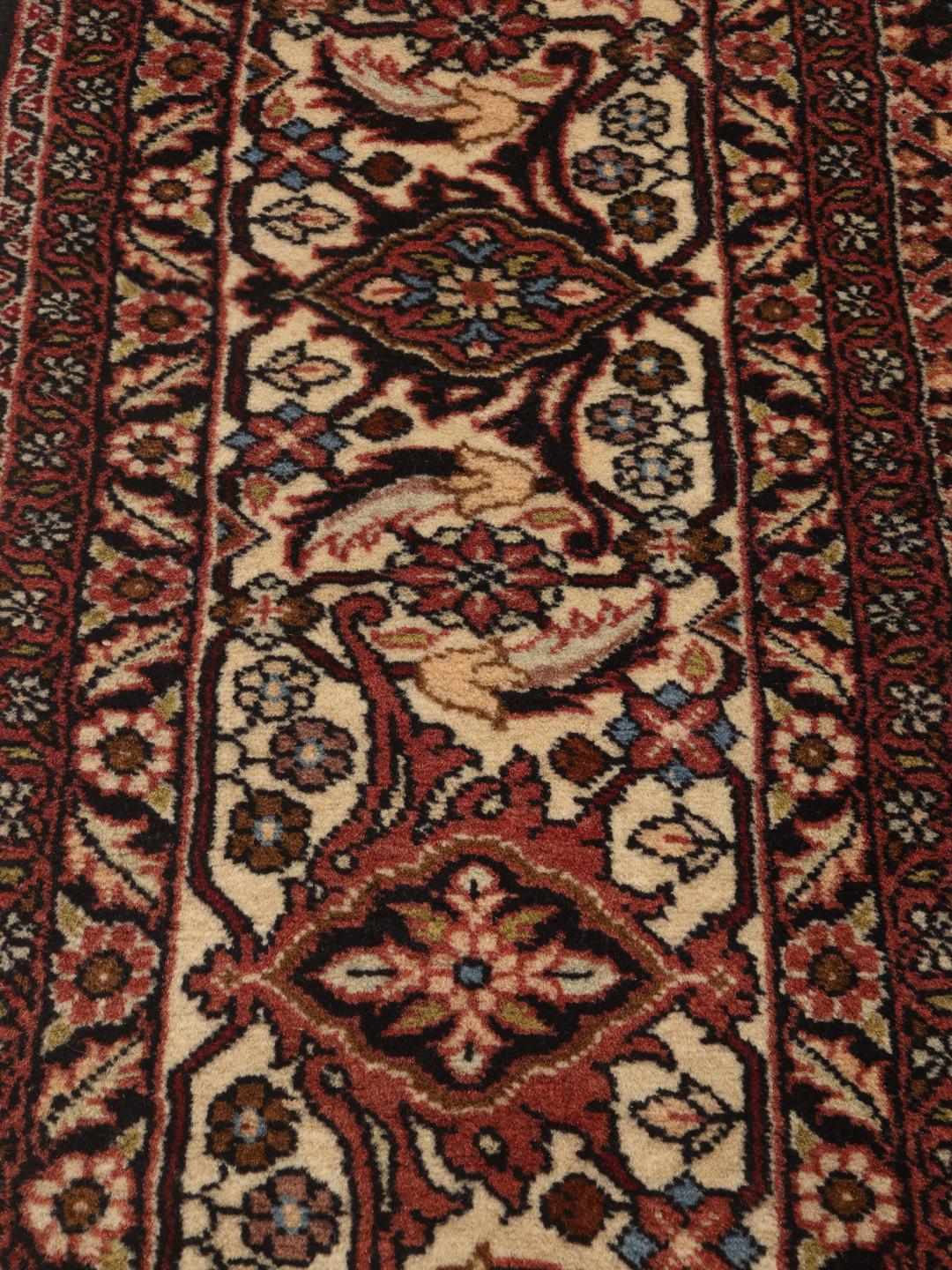 A hand-knotted Bidjar rug from the Middle East with a dark-red field and intricate medallion pattern.