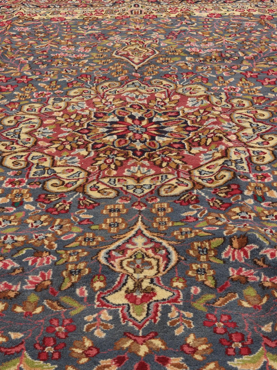 Handgeknoopt Kerman-tapijt met een blauw bloemenmedaillon en rode rand