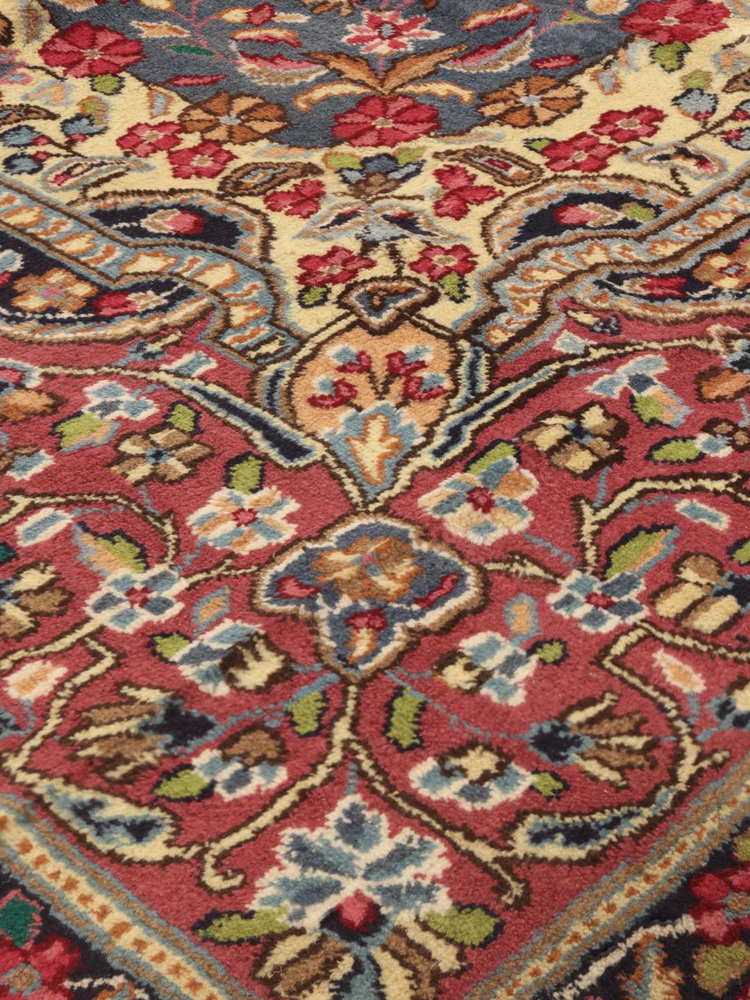 Handgeknoopt Kerman-tapijt met een blauw bloemenmedaillon en rode rand
