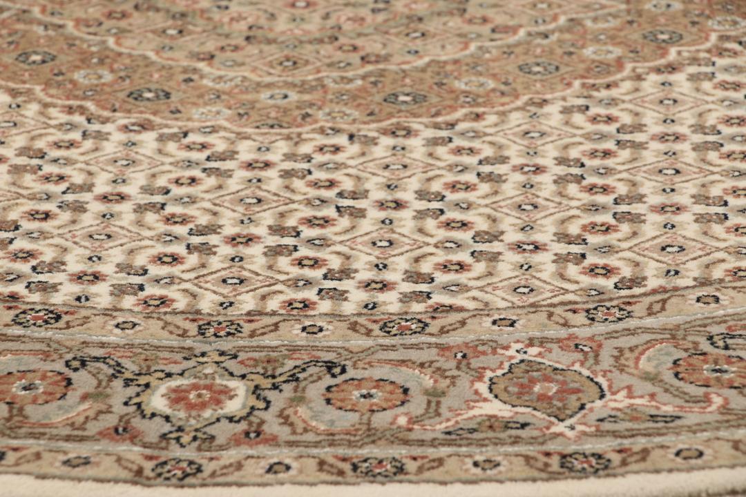 Rundt Tabriz-tæppe med indviklede mønstre i beige, brun og rød, håndlavet i Indien.