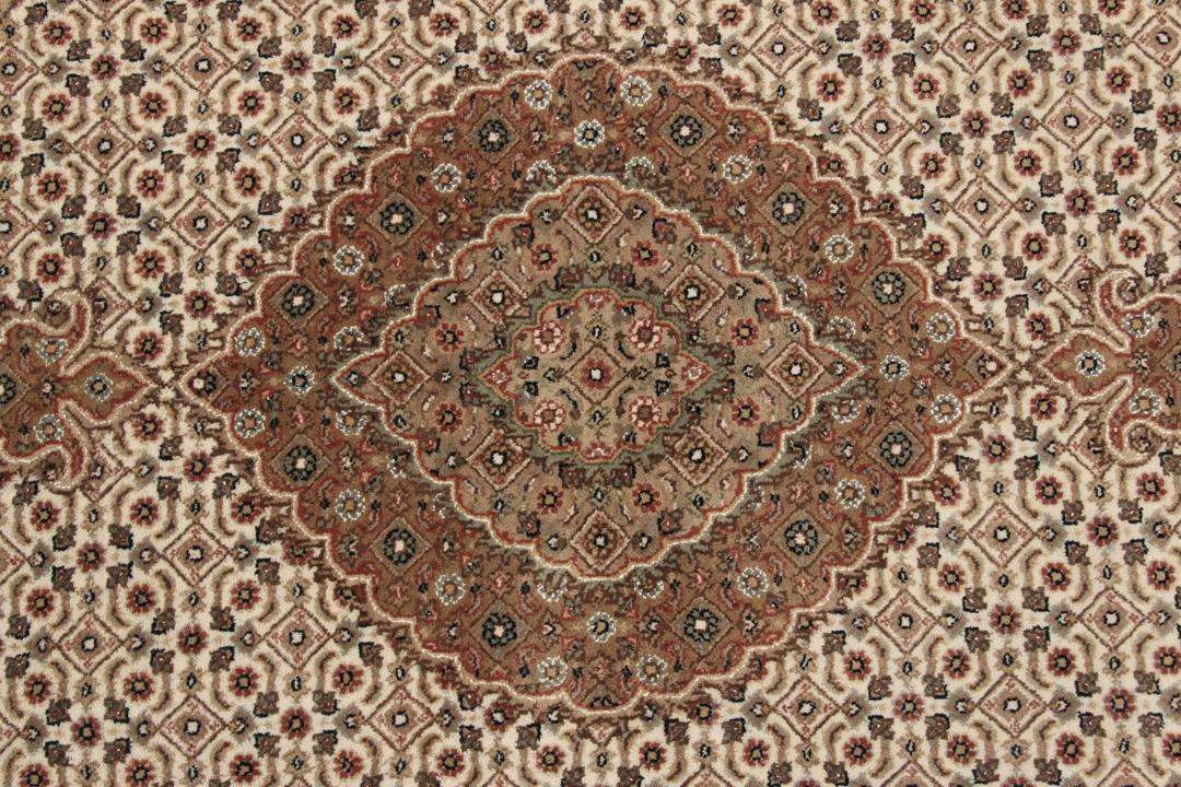 Rundt Tabriz-tæppe med indviklede mønstre i beige, brun og rød, håndlavet i Indien.