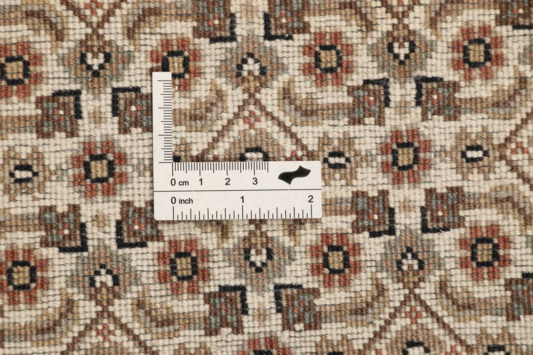 Rundt Tabriz-tæppe med indviklede mønstre i beige, brun og rød, håndlavet i Indien.