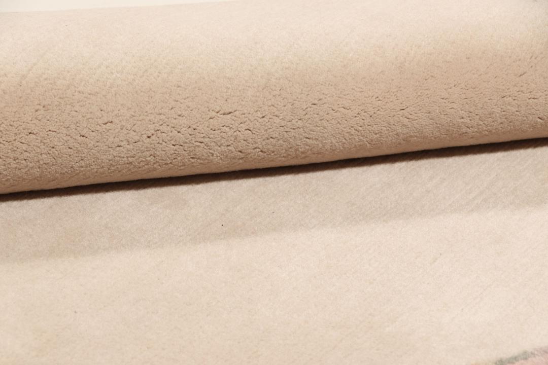 Een rond, uniek Wool tapijt uit Nepal met een minimalistisch beige en zachtroze ontwerp.
