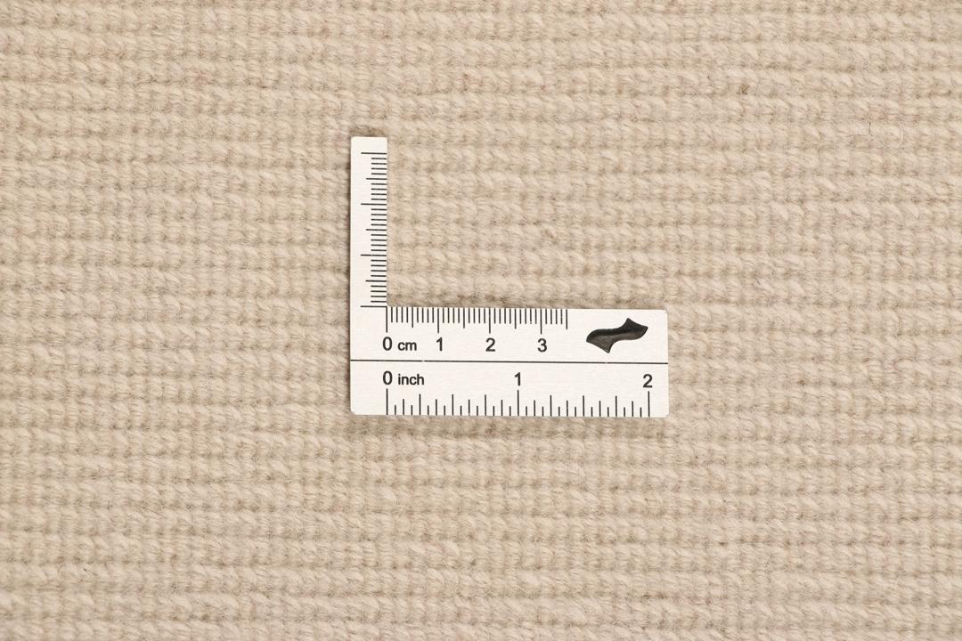 Een rond, uniek Wool tapijt uit Nepal met een minimalistisch beige en zachtroze ontwerp.