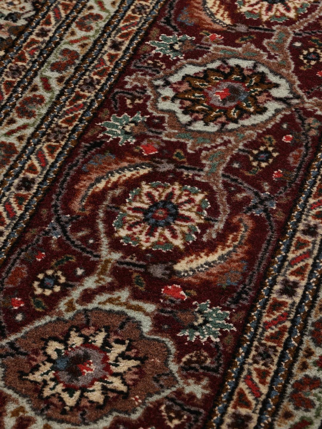 Et håndknyttet Tabriz-tæppe fra Mellemøsten med et detaljeret rødt og beige mønster