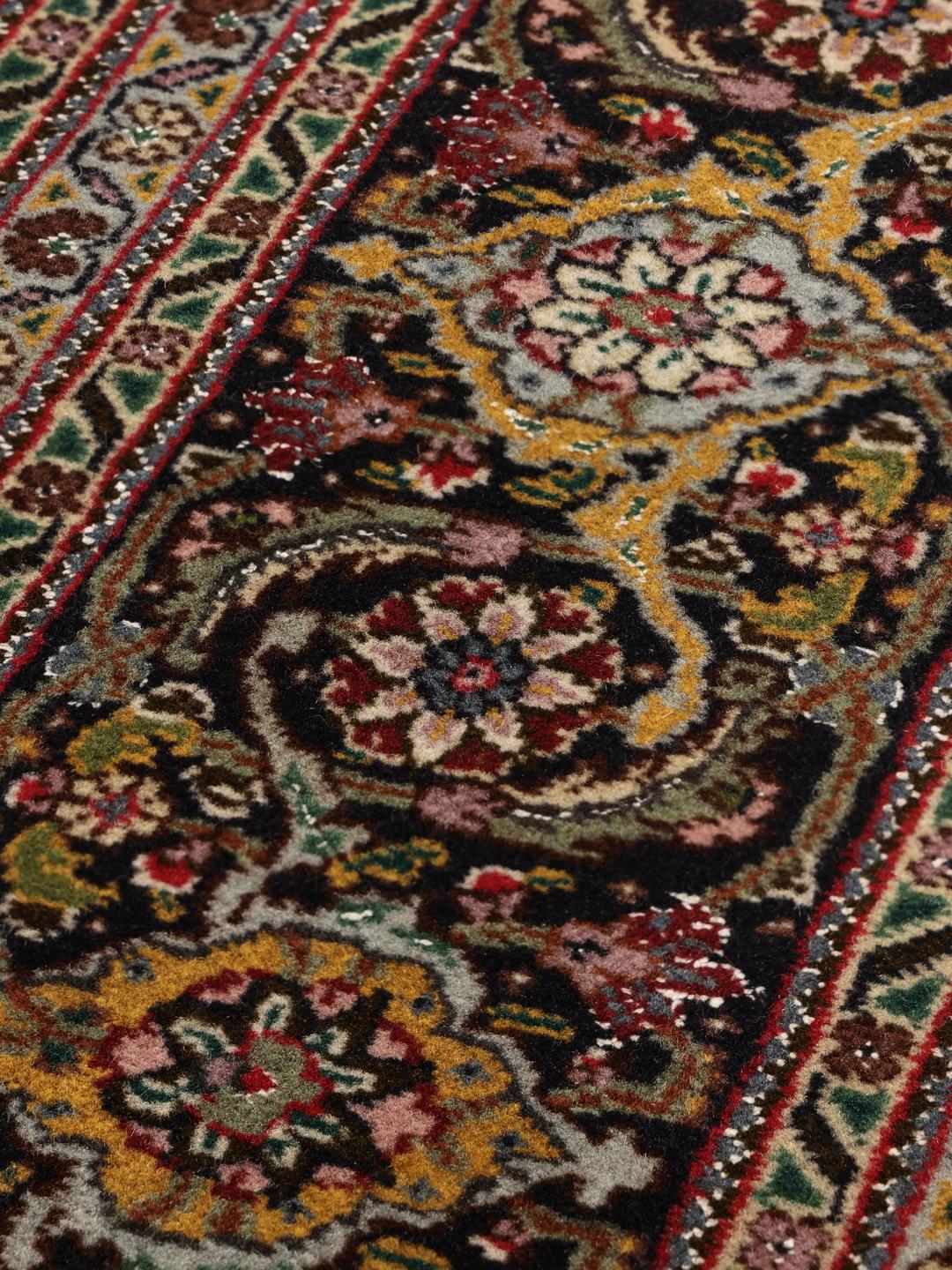 Et håndknyttet Tabriz-tæppe fra Mellemøsten med en mørkerød bund og et detaljeret medaljondesign.