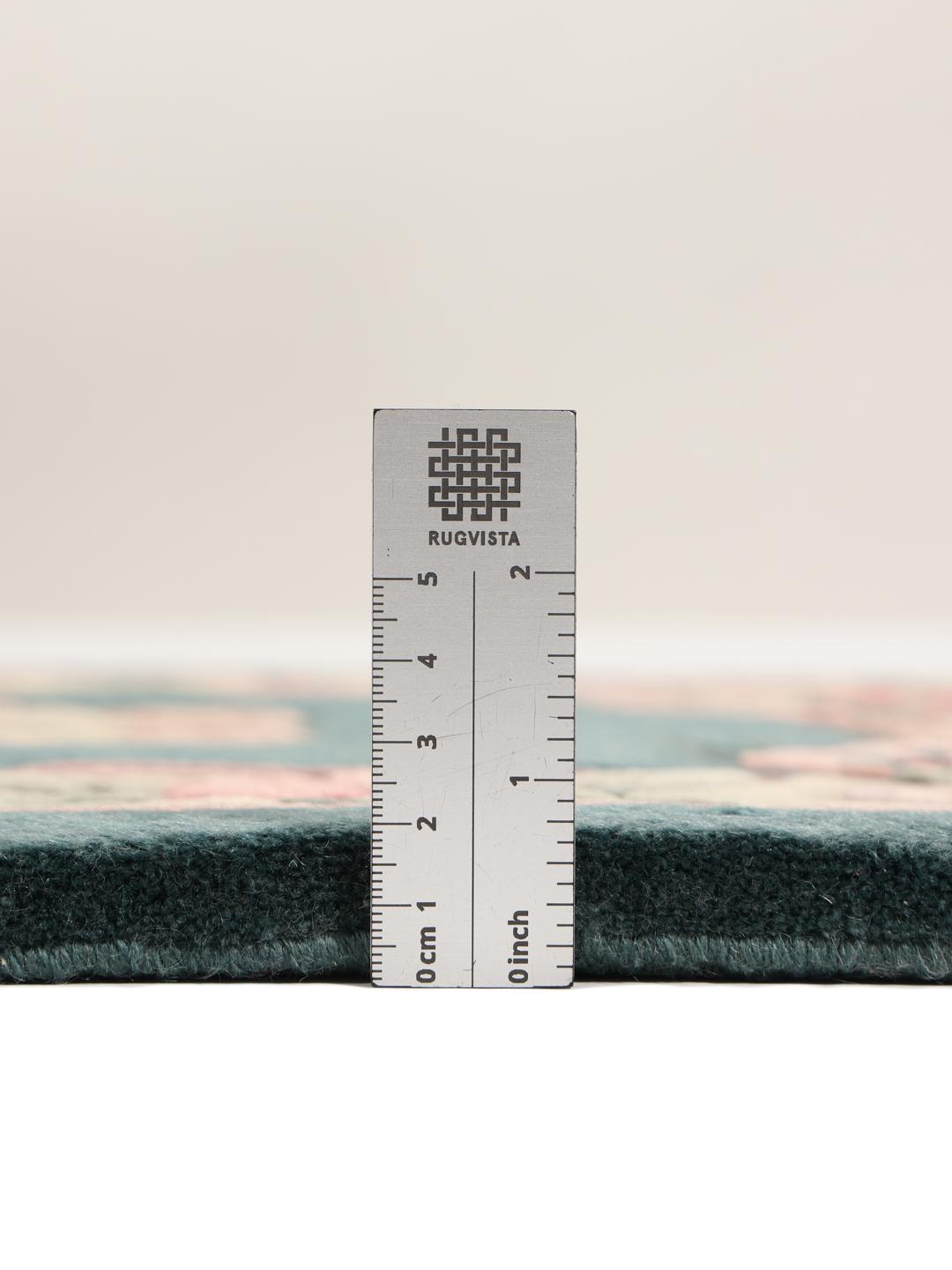 Et rektangulært uldtæppe fra Kina med en teal baggrund og lyserøde blomstermønstre.