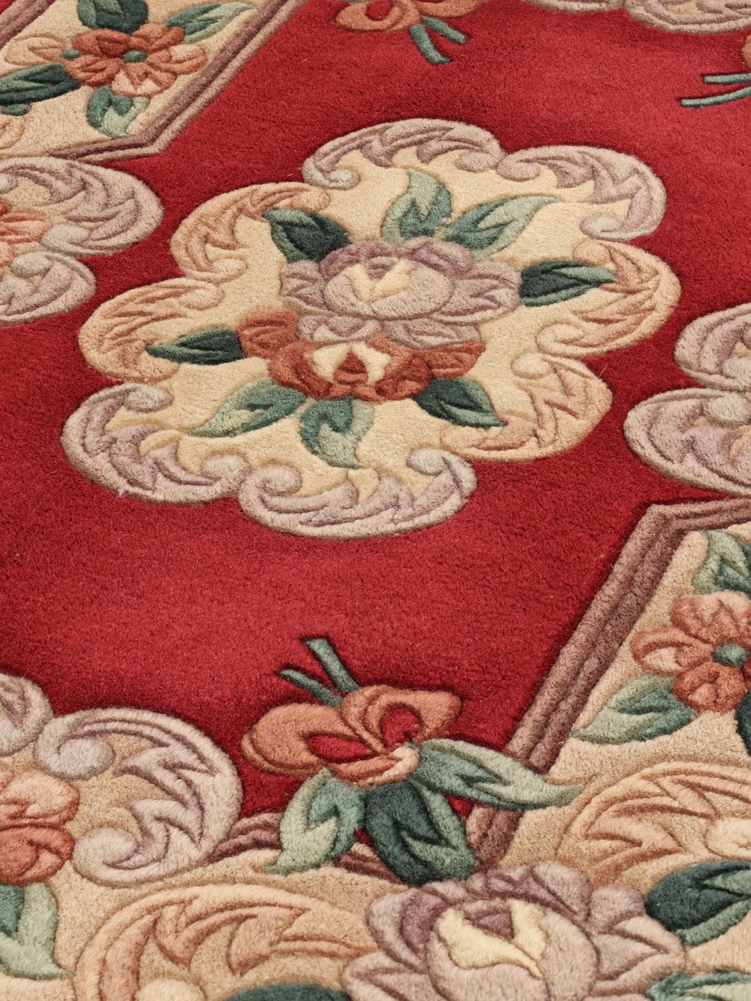 A rectangular hand-knotted Chinese rug with a red field and intricate floral medallion motifs.