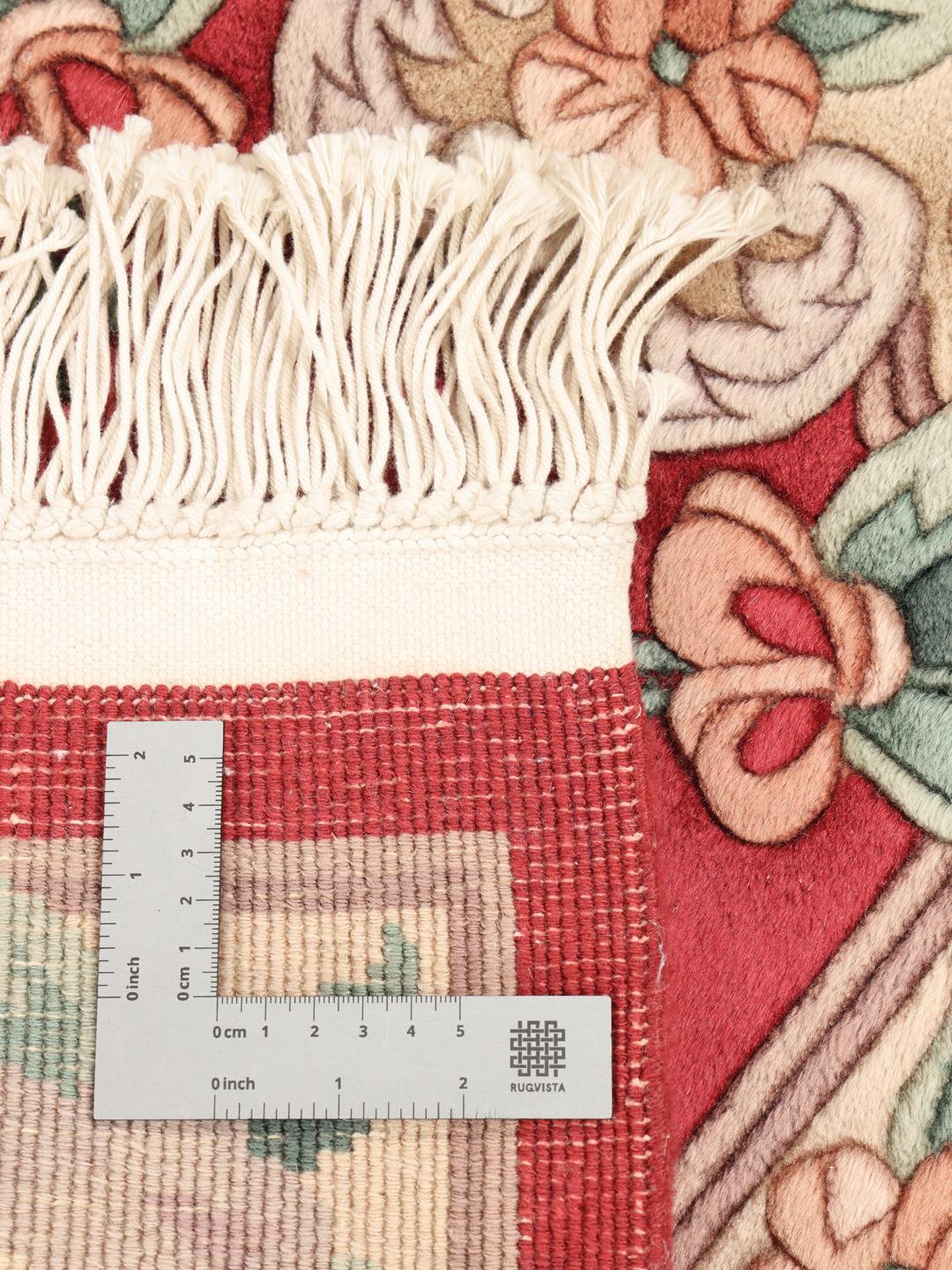 A rectangular hand-knotted Chinese rug with a red field and intricate floral medallion motifs.
