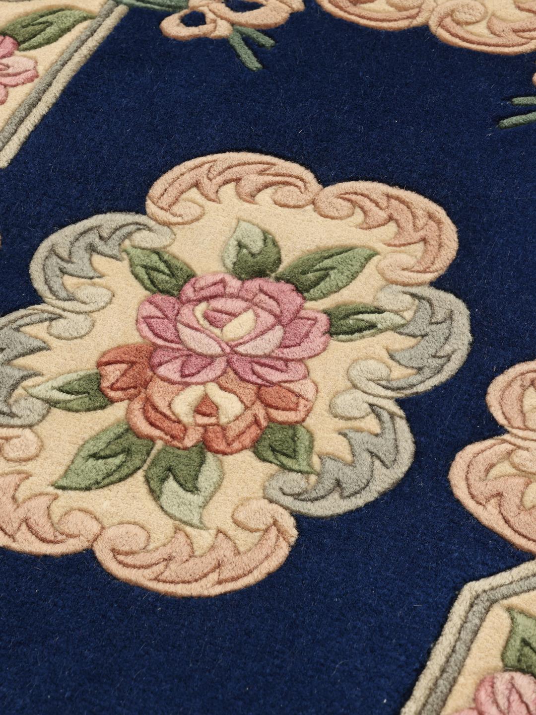 Een met de hand geknoopt tapijt uit China met een bloemenpatroon op een blauwe achtergrond.