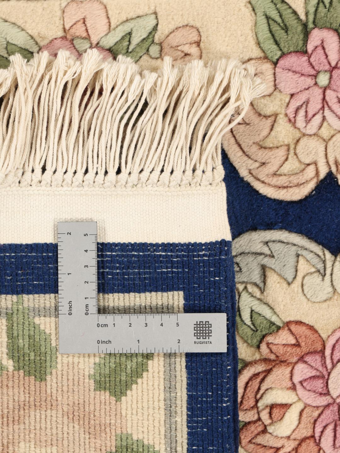 Een met de hand geknoopt tapijt uit China met een bloemenpatroon op een blauwe achtergrond.