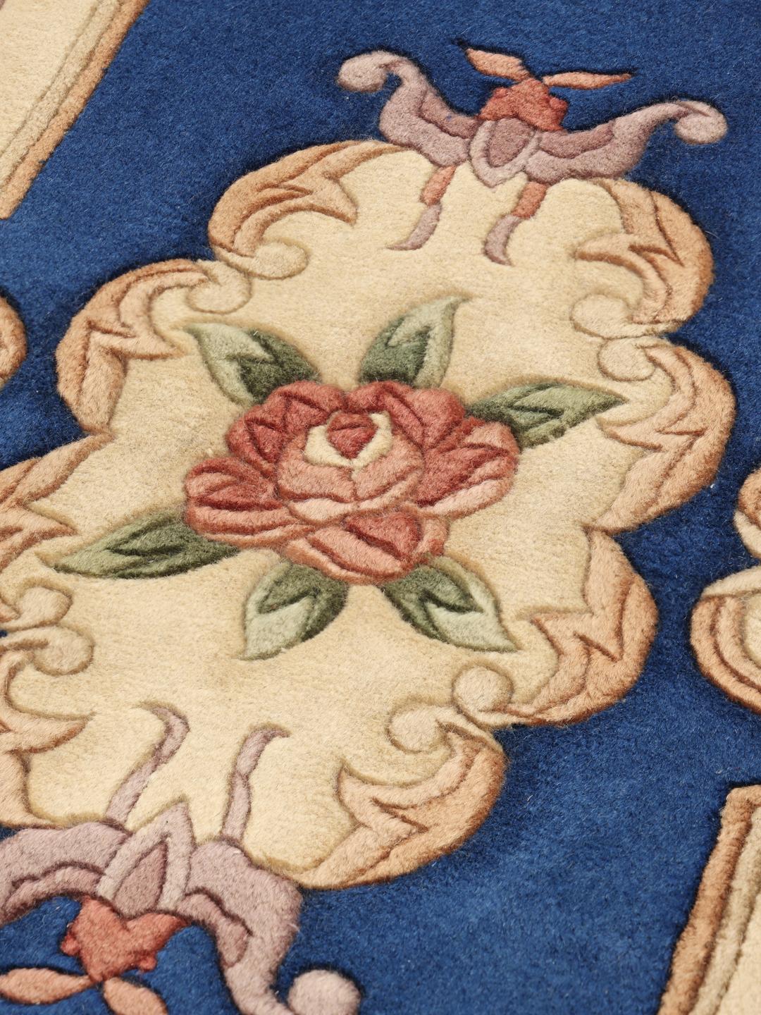 Håndknyttet kinesisk tæppe med blomstermønster i blå og beige.