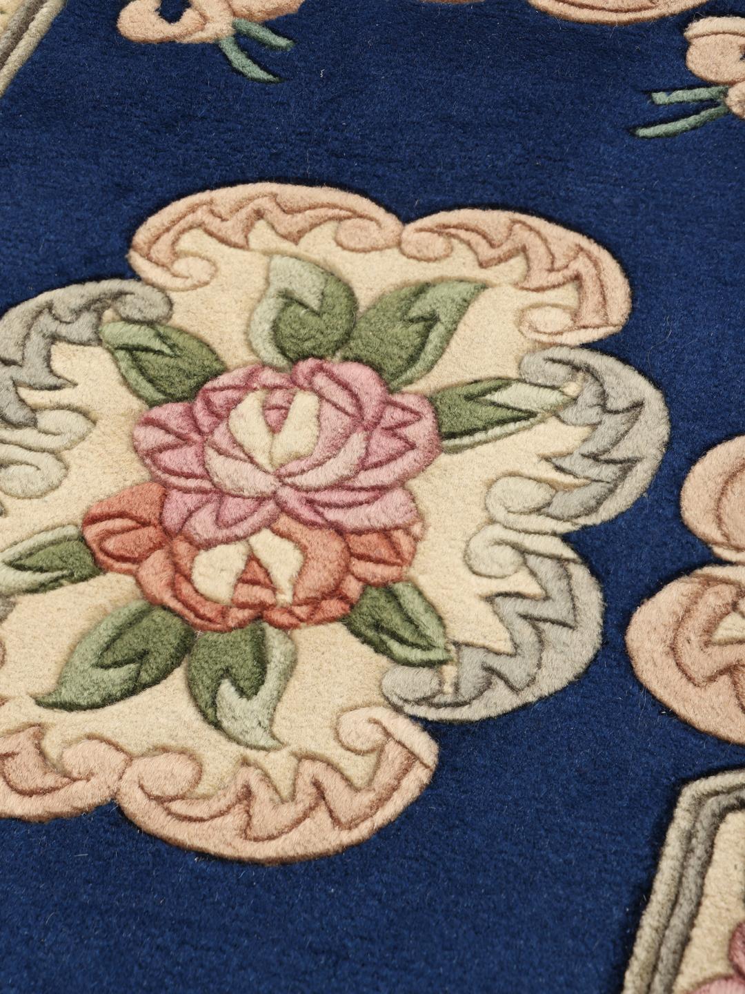 Een handgeknoopt Chinees tapijt met een bloemenpatroon en een blauwe achtergrond.