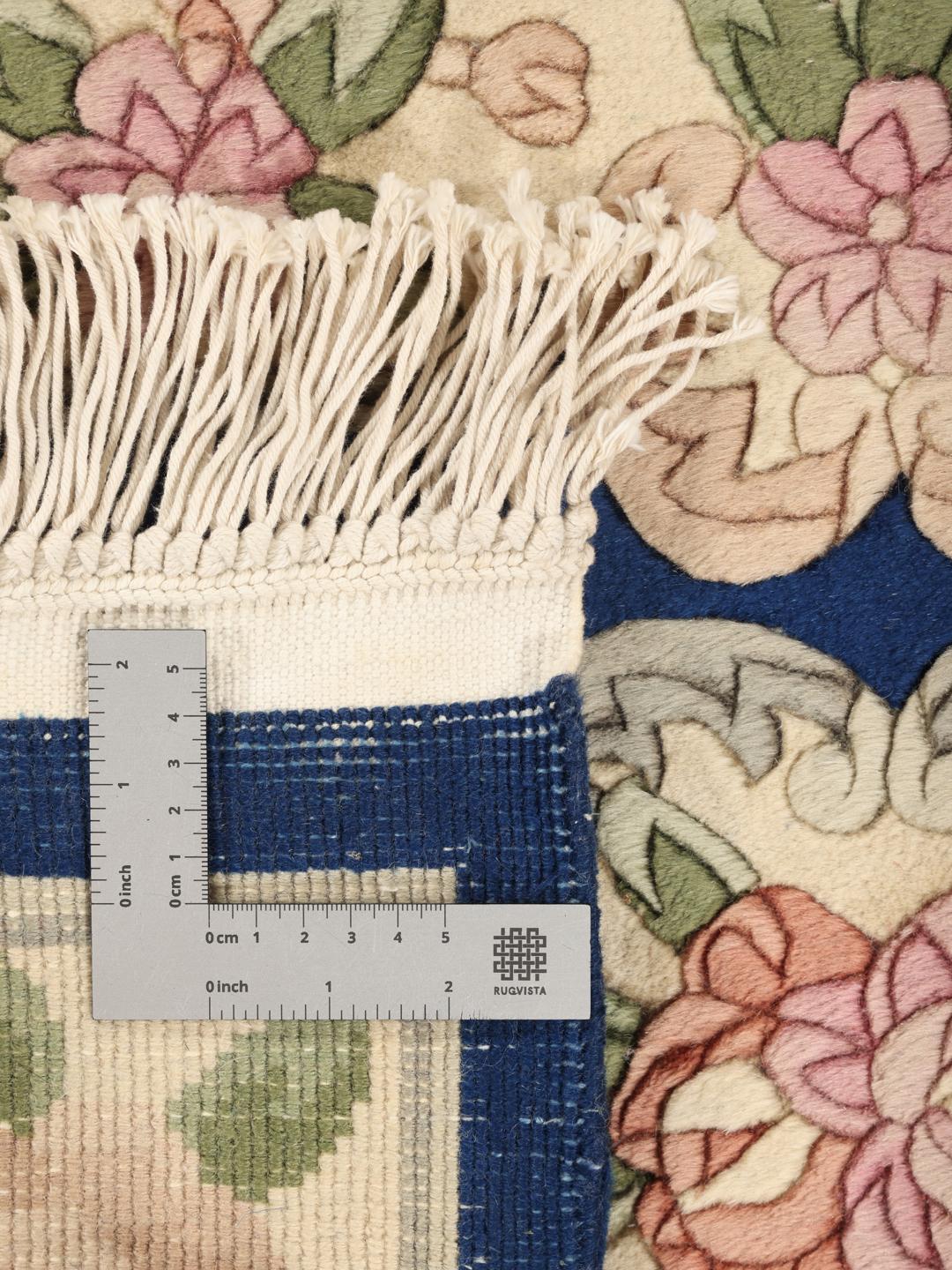 Een handgeknoopt Chinees tapijt met een bloemenpatroon en een blauwe achtergrond.