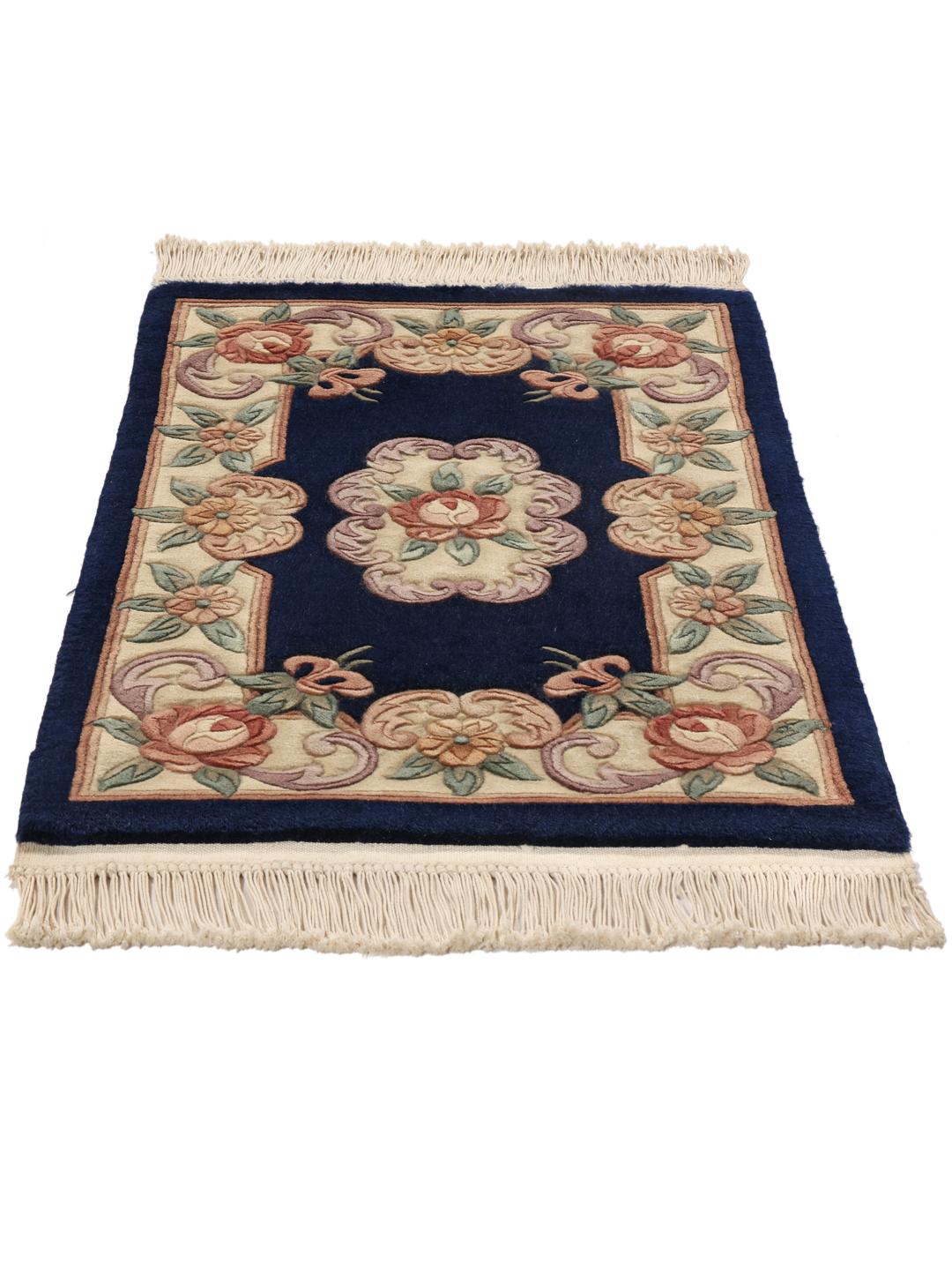 A hand-knotted Chinese rug with floral motifs on a deep blue background.