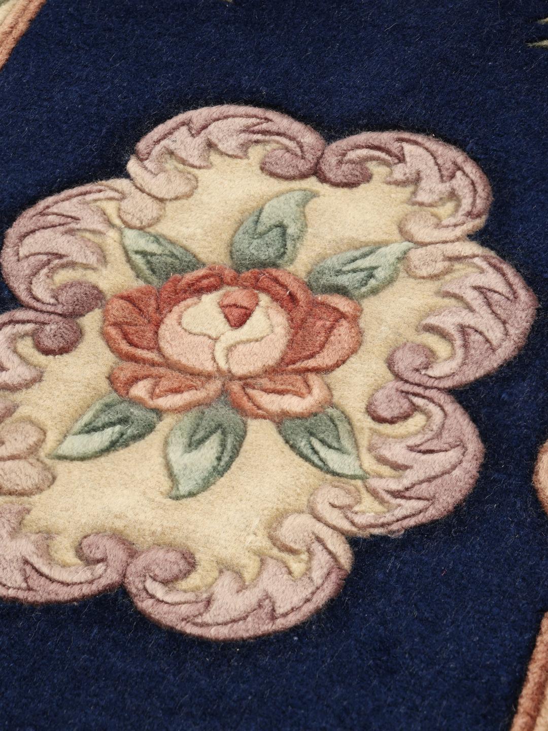 A hand-knotted Chinese rug with floral motifs on a deep blue background.