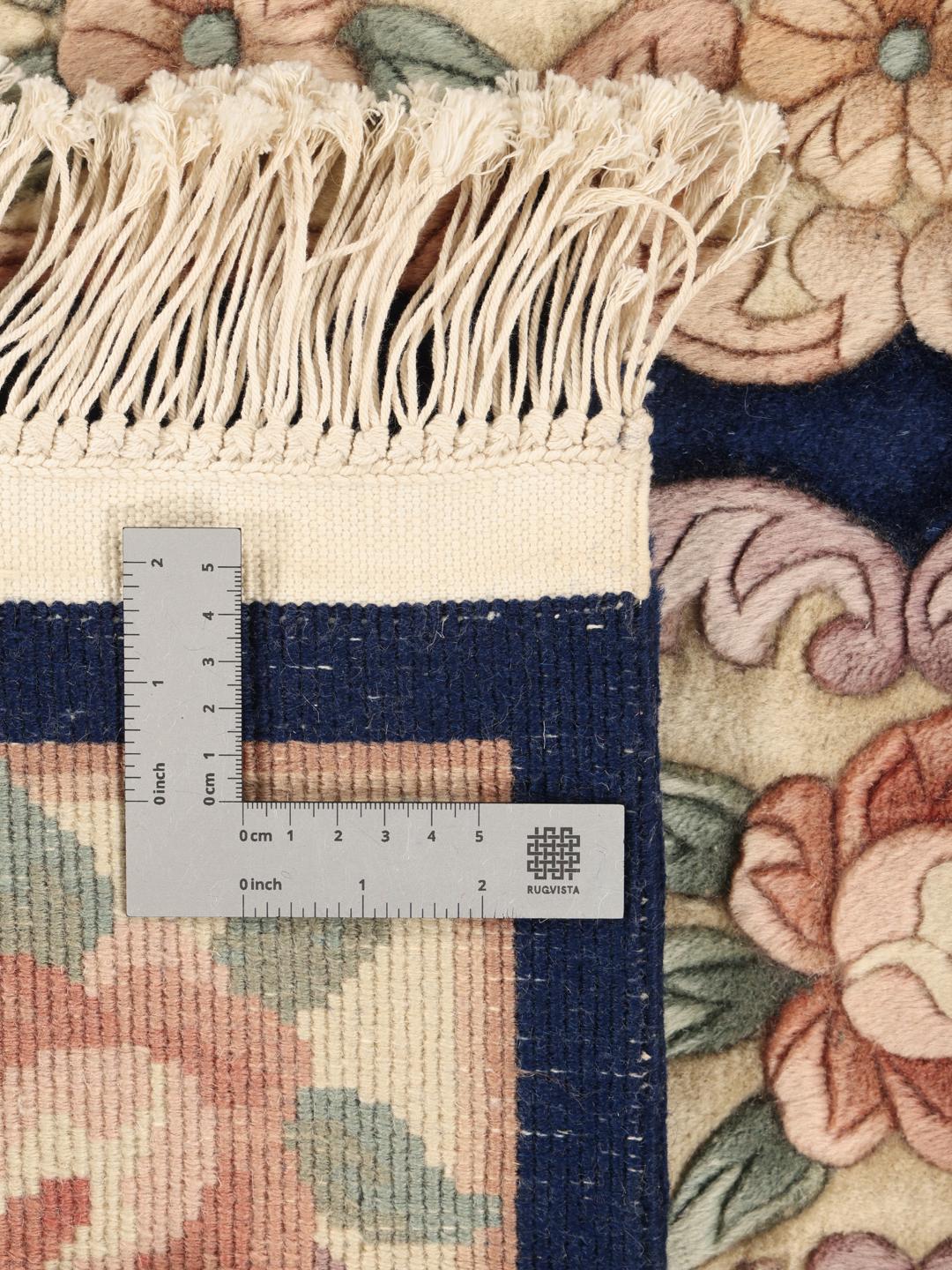 A hand-knotted Chinese rug with floral motifs on a deep blue background.